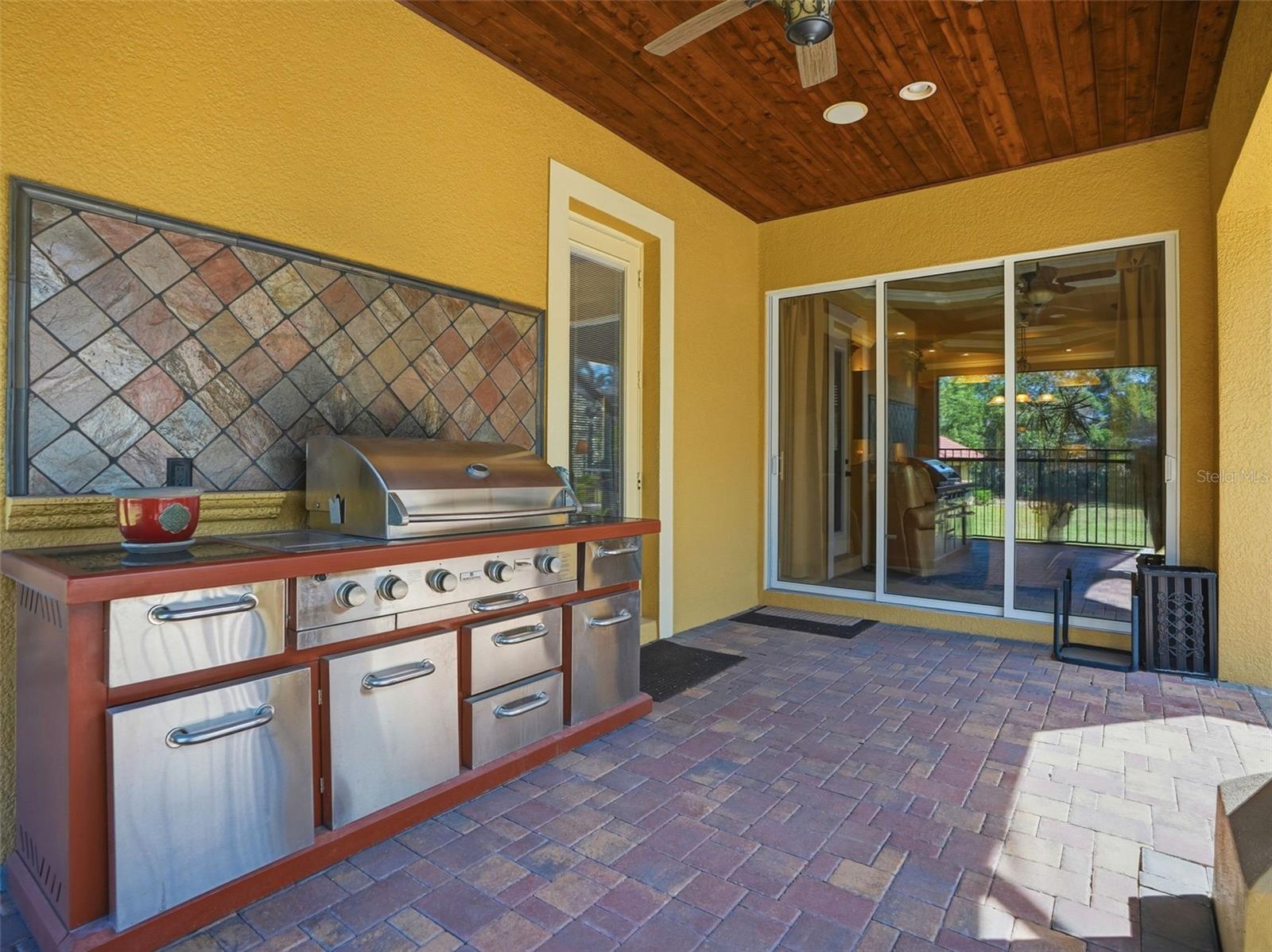 Outdoor kitchen with propane grill and seating area overlooking the pool. Easy access to the kitchen.