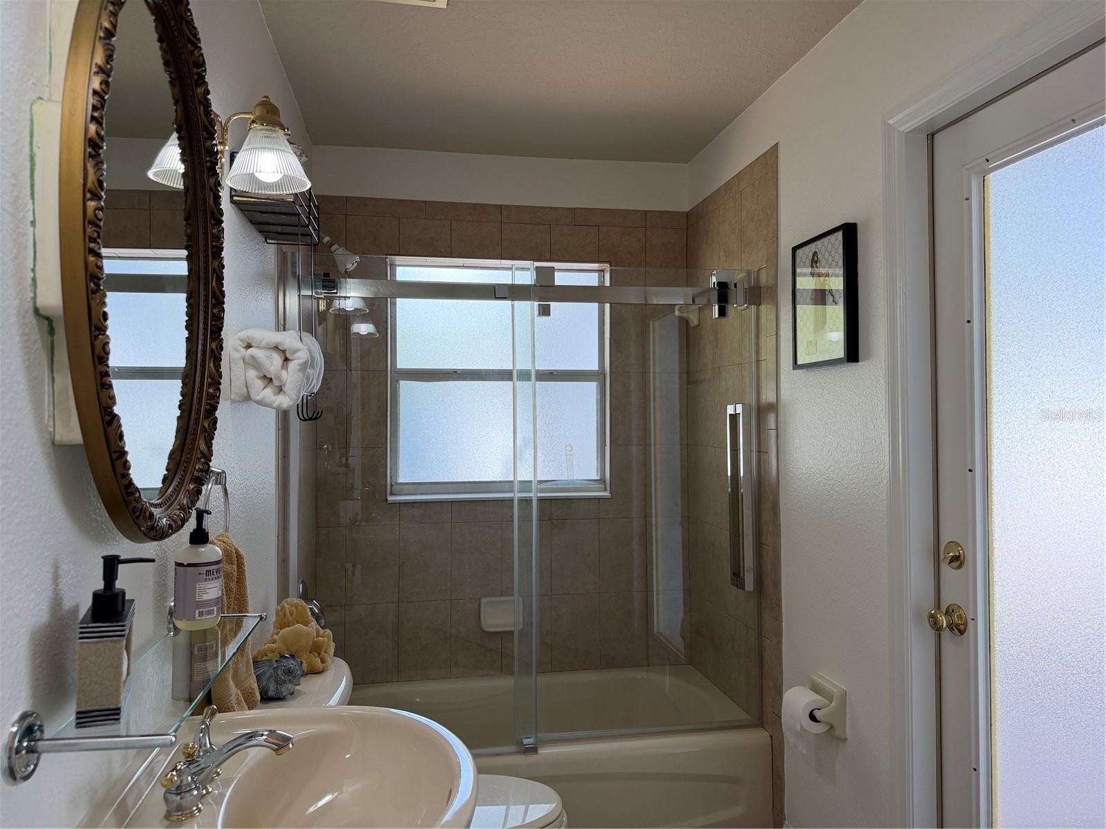 2nd bathroom has tub with shower and a quality sliding shower door