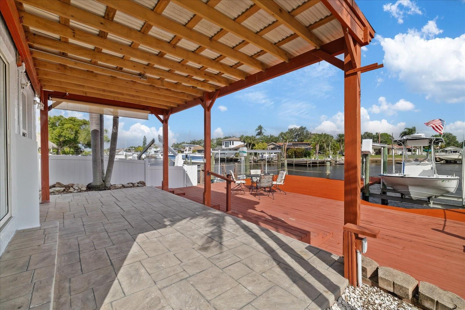 Back covered patio and deck over seawall with boat lift on wide North Channel