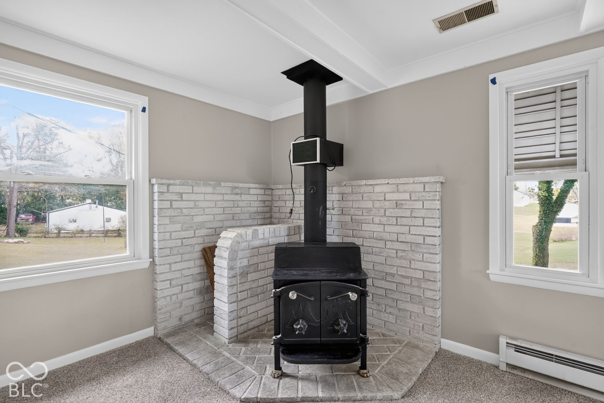 Cast iron wood-burning stove featuring a tiered brick hearth and painted brick surround