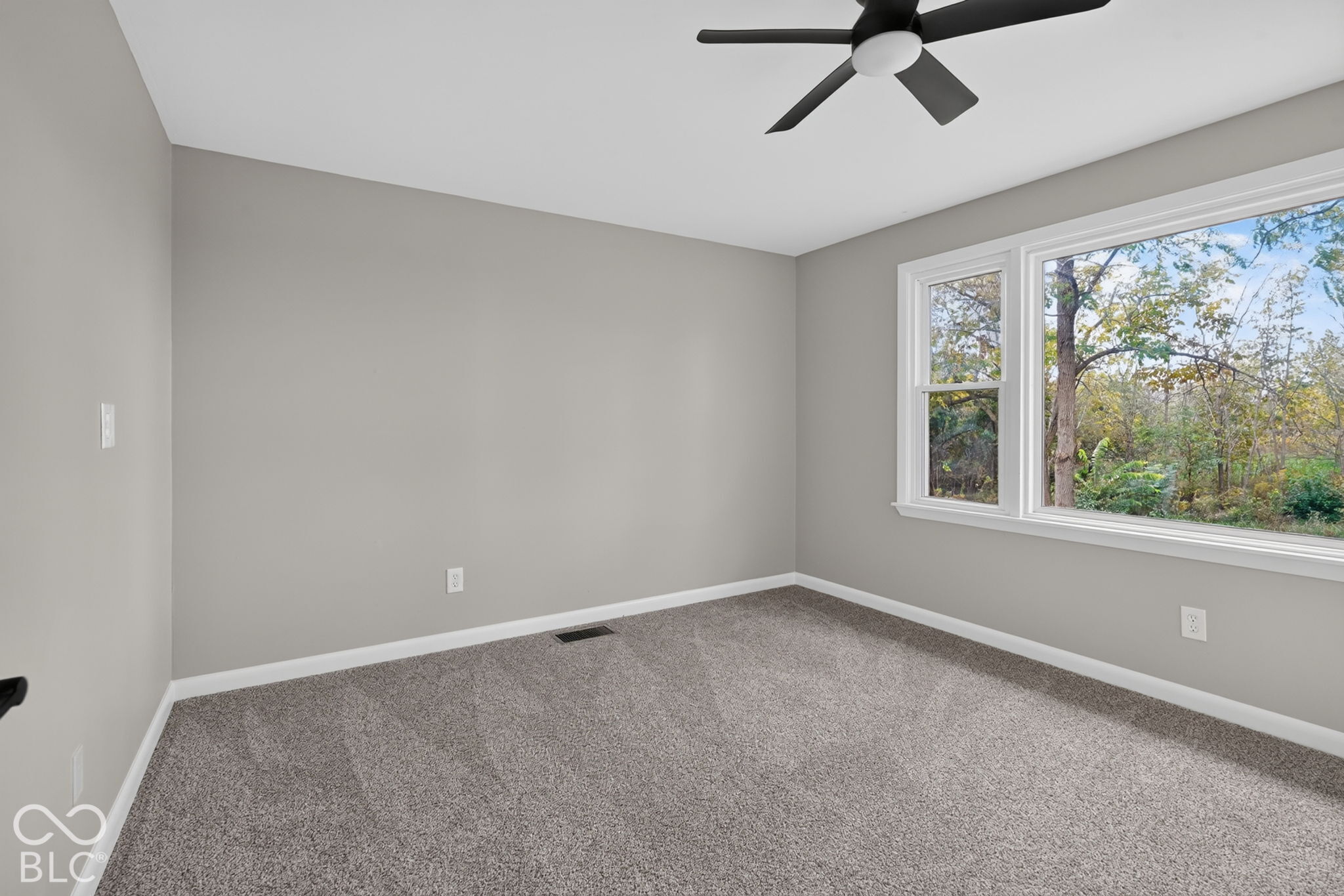 Neutral wall color, carpeted flooring, large window with outdoor scenery, and ceiling-mounted light fixture