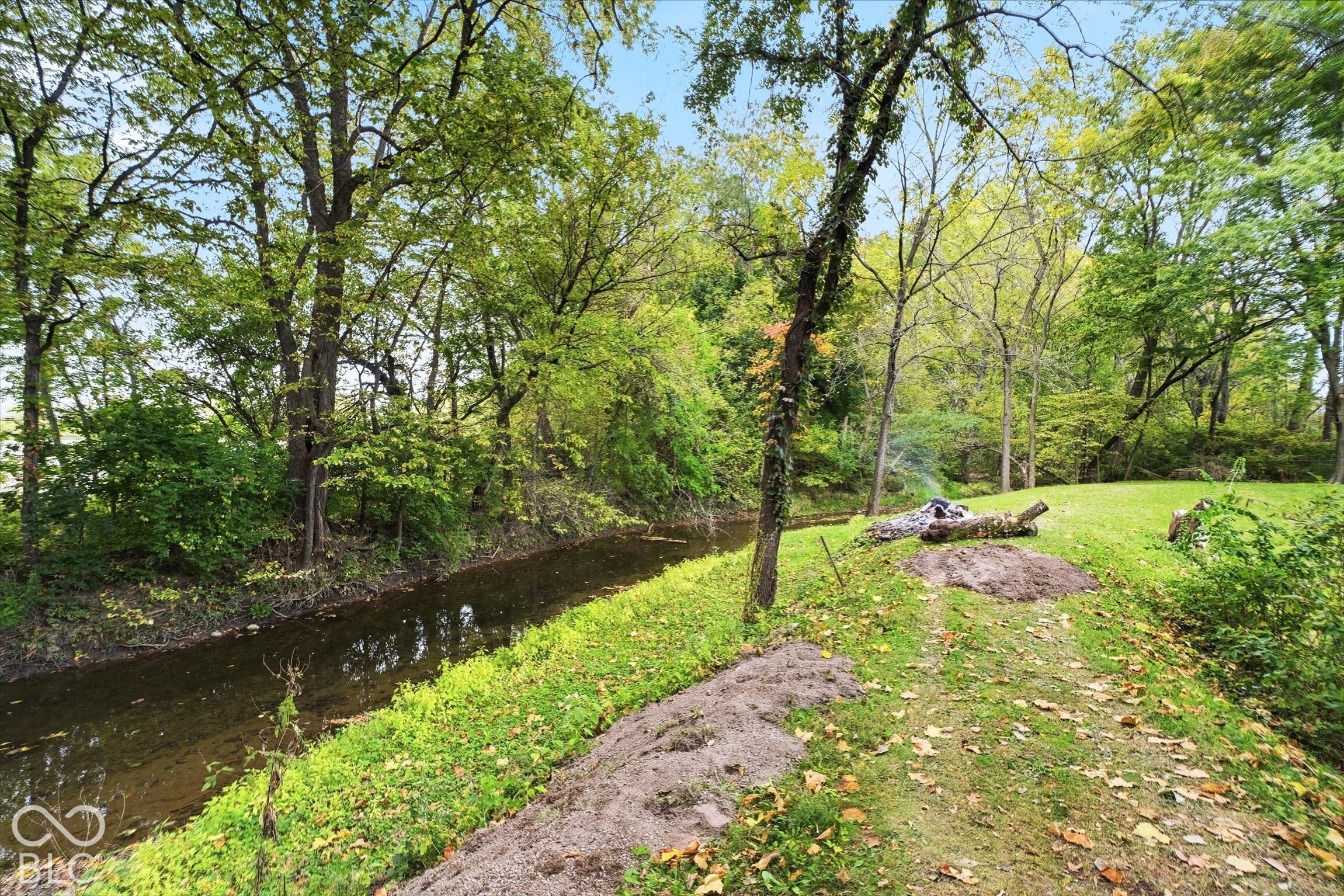 Expansive greenspace with mature trees and a natural water feature