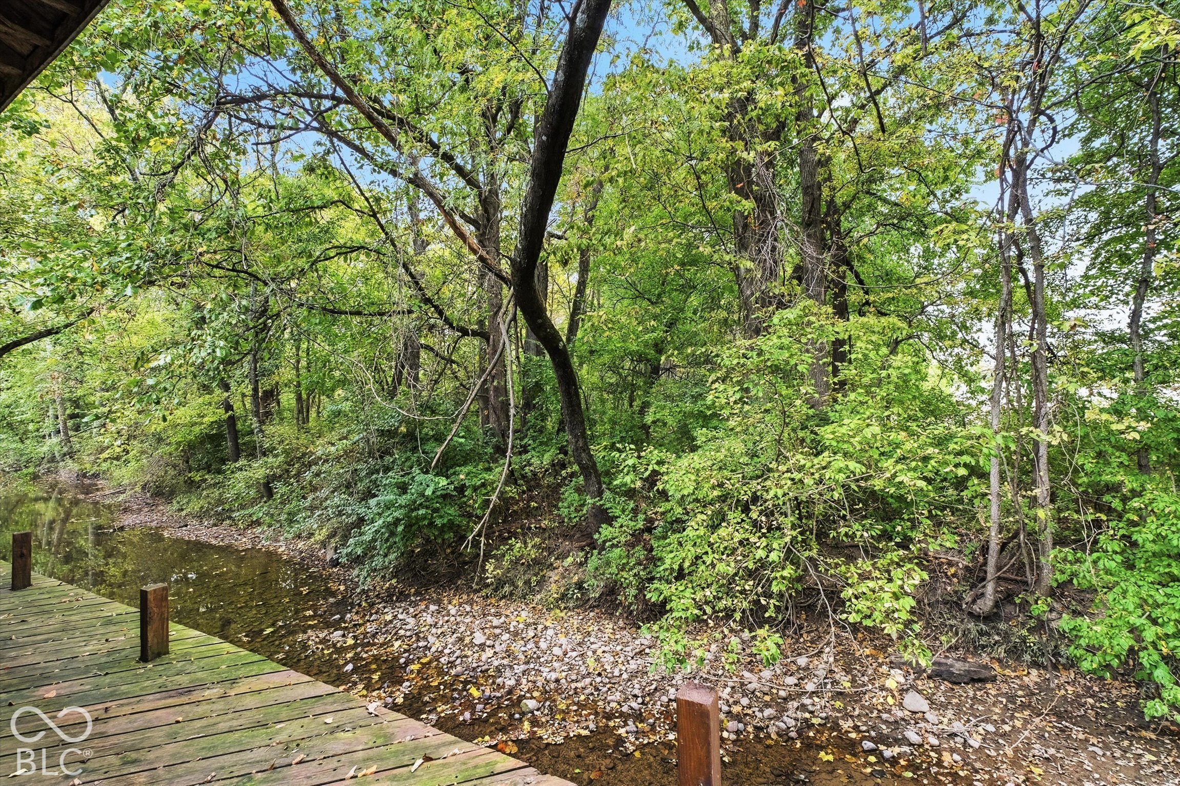 Barn has a back deck looking over the creek on a tree-lined bank