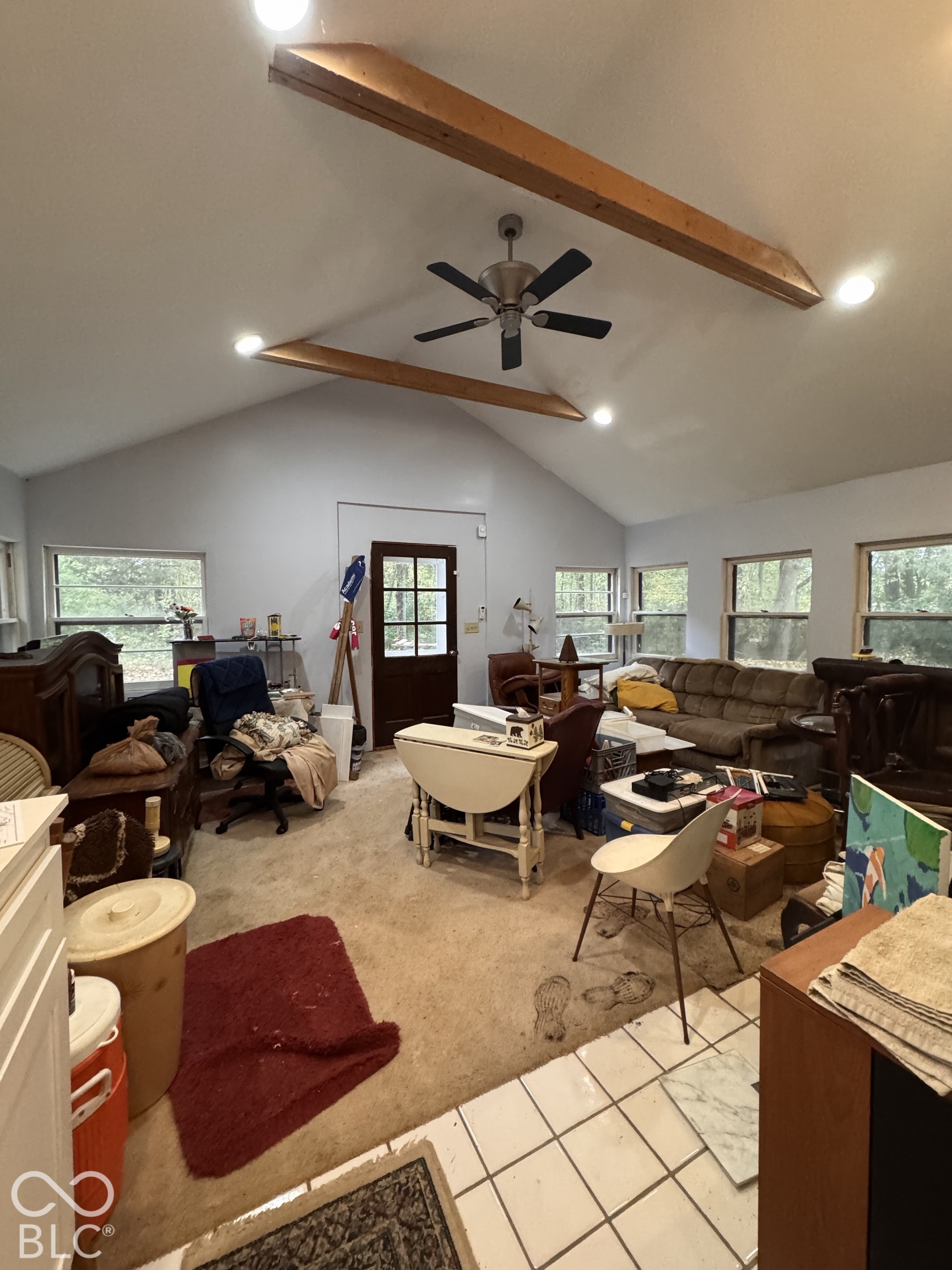 Vaulted ceiling featuring exposed wood beams, ceiling fan, and recessed lighting, and an exterior access door leading to the deck