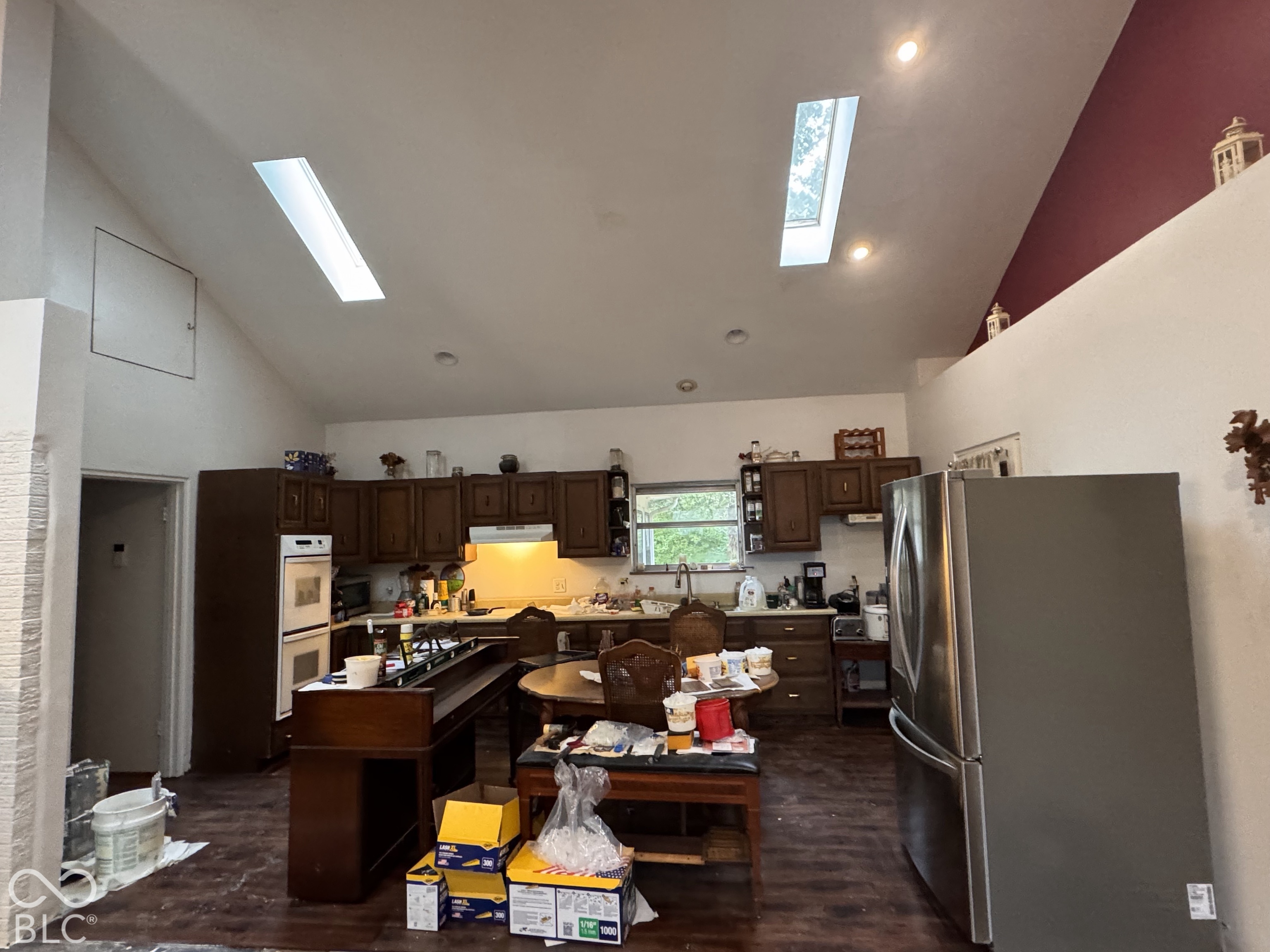 Vaulted ceiling featuring two skylights, recessed lighting, wood-finish flooring, and cabinetry