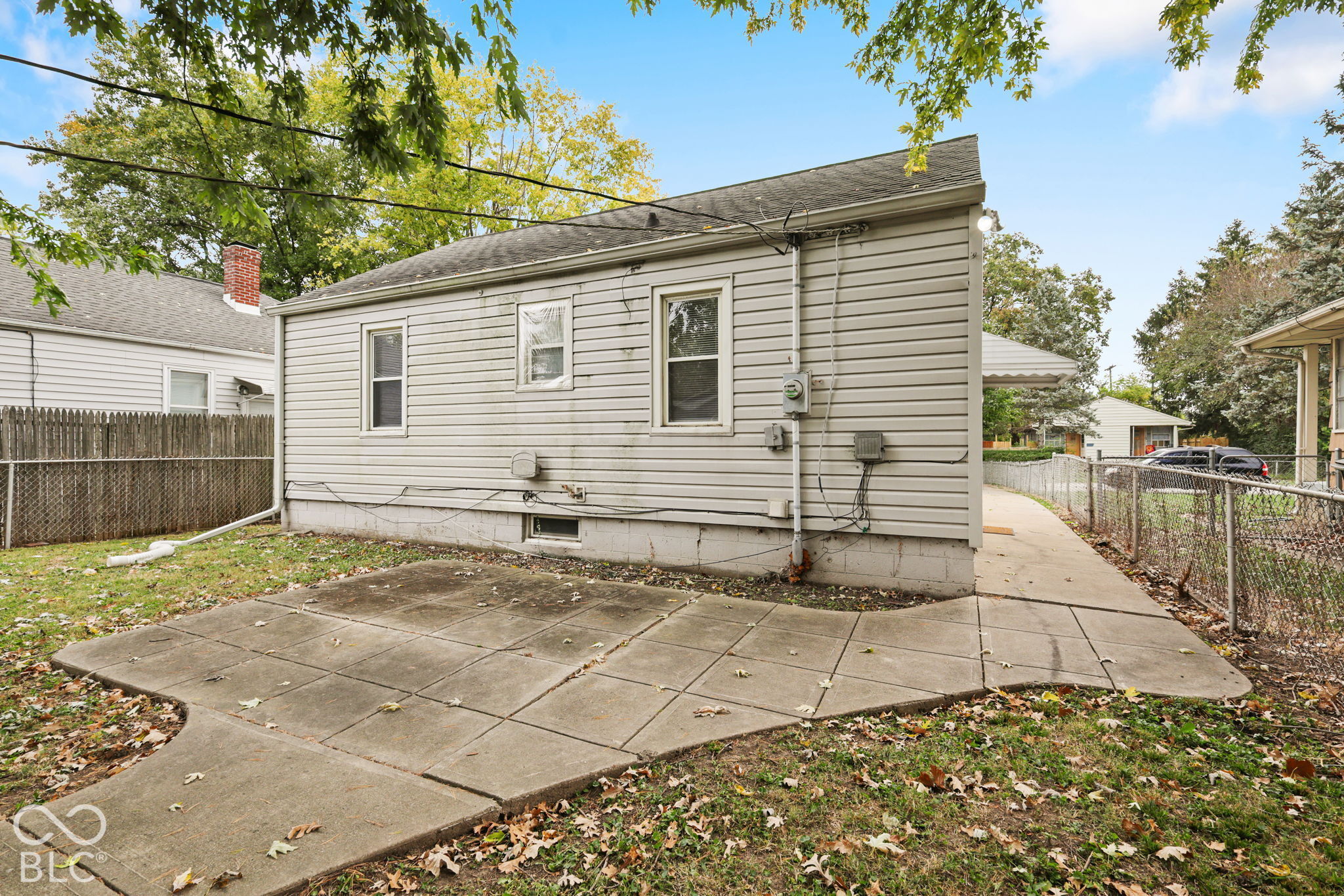 Exterior view featuring horizontal siding, a concrete patio, and chain-link perimeter fencing
