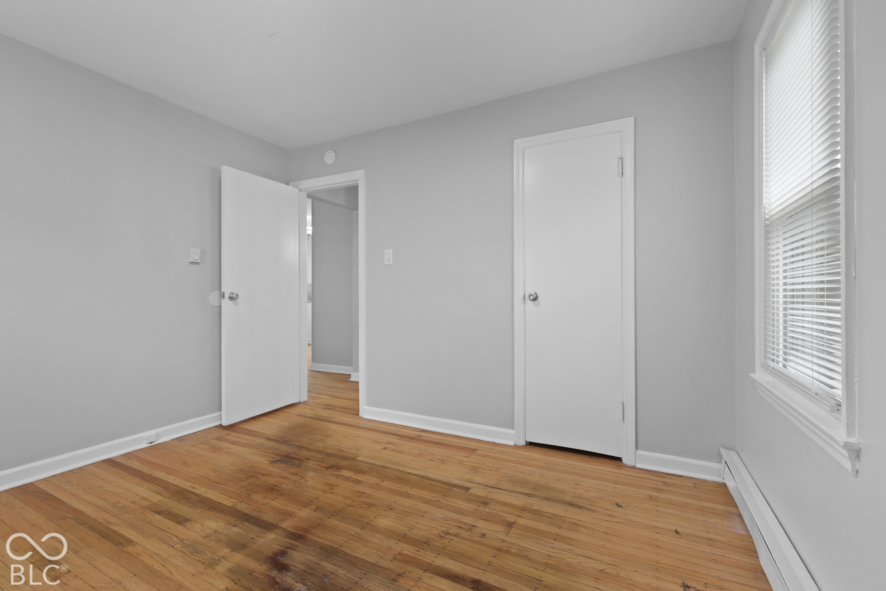 Room featuring wood-finish flooring, neutral wall paint, and white paneled doors