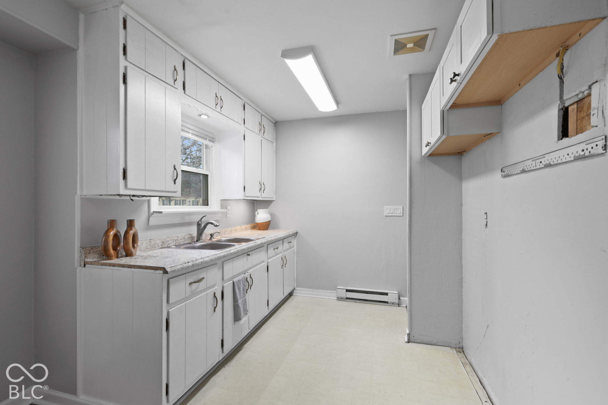 Kitchen featuring white cabinetry, stone-finish countertops, stainless steel dual-basin sink with pull-down faucet, and overhead LED lighting