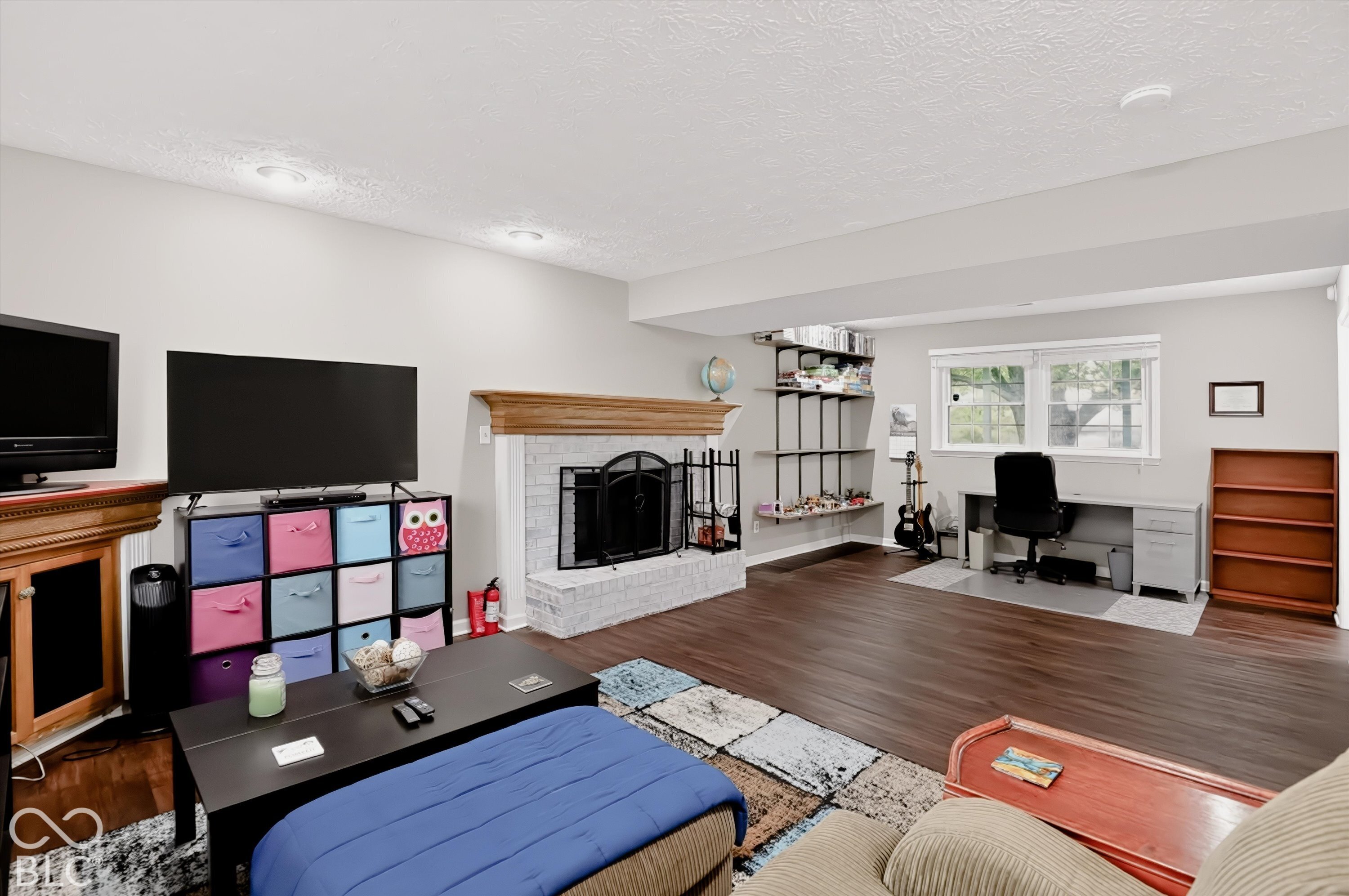 Living space featuring a brick fireplace with a wood mantel, wood-finish flooring, and recessed lighting