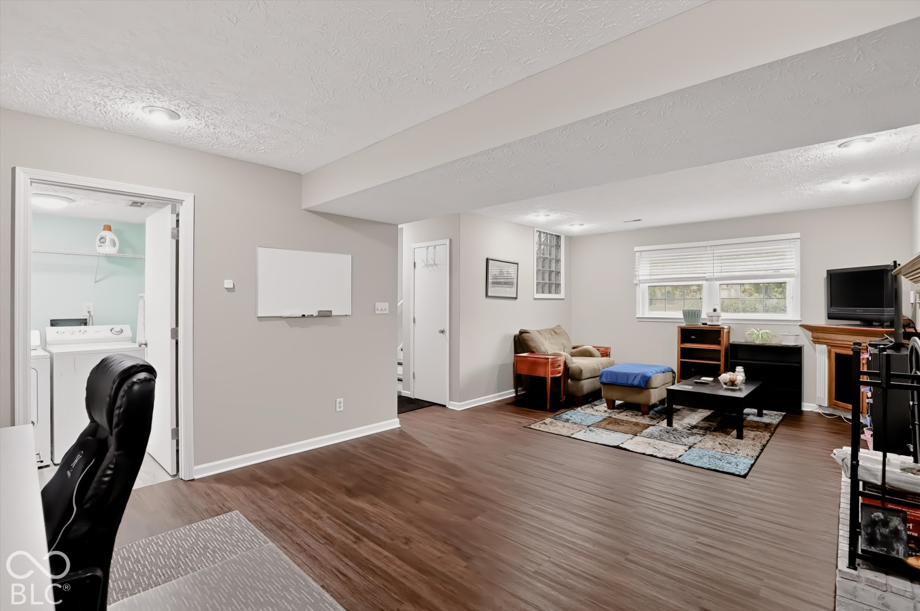 Open-concept room featuring wood-finish flooring, recessed lighting, a brick fireplace, and a laundry room entry