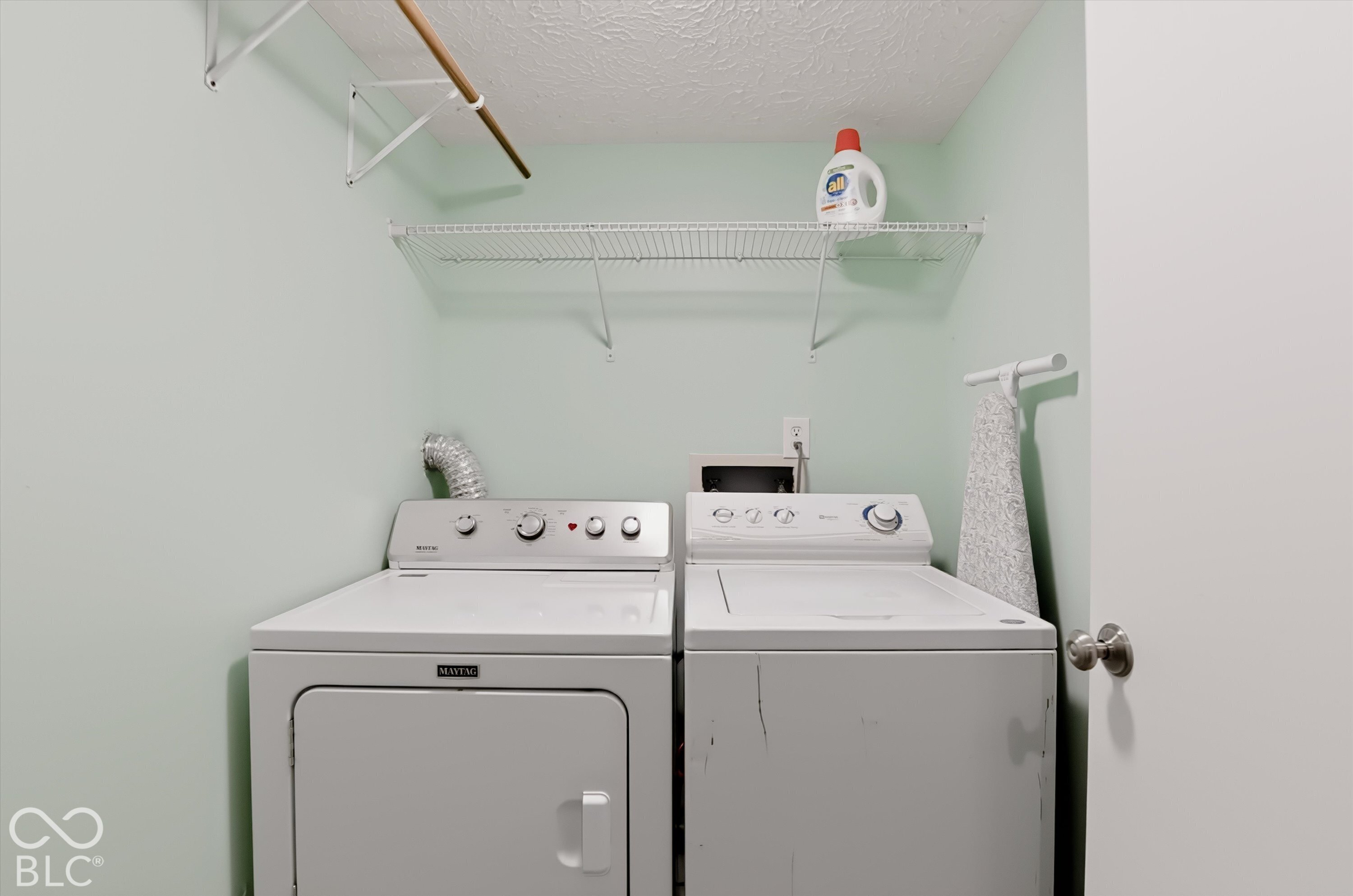 Laundry area featuring dual wire shelving and a mounted garment rod
