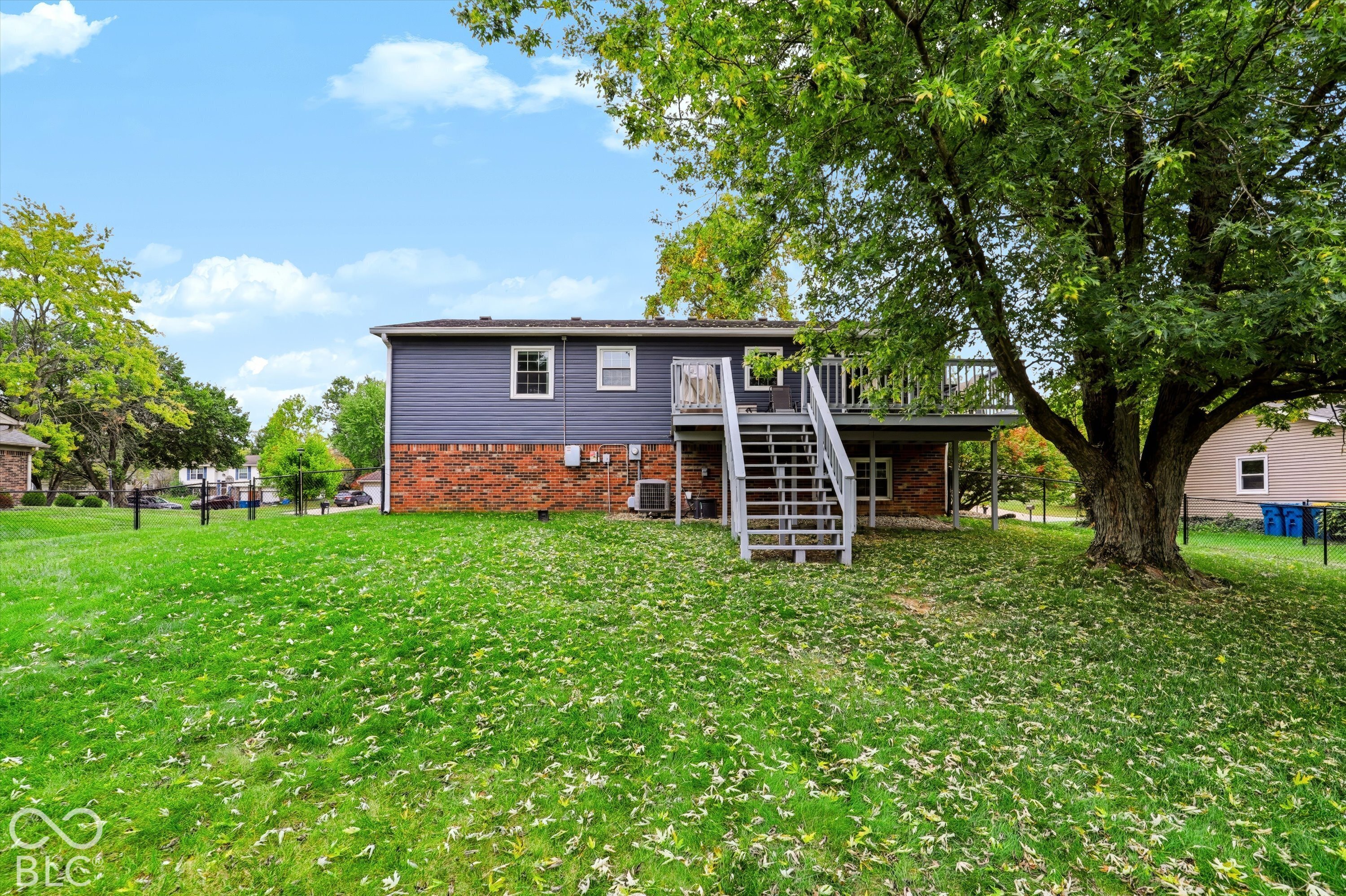 Exterior featuring a partial brick and horizontal lap siding facade, an elevated rear deck with stairs, and a mature tree