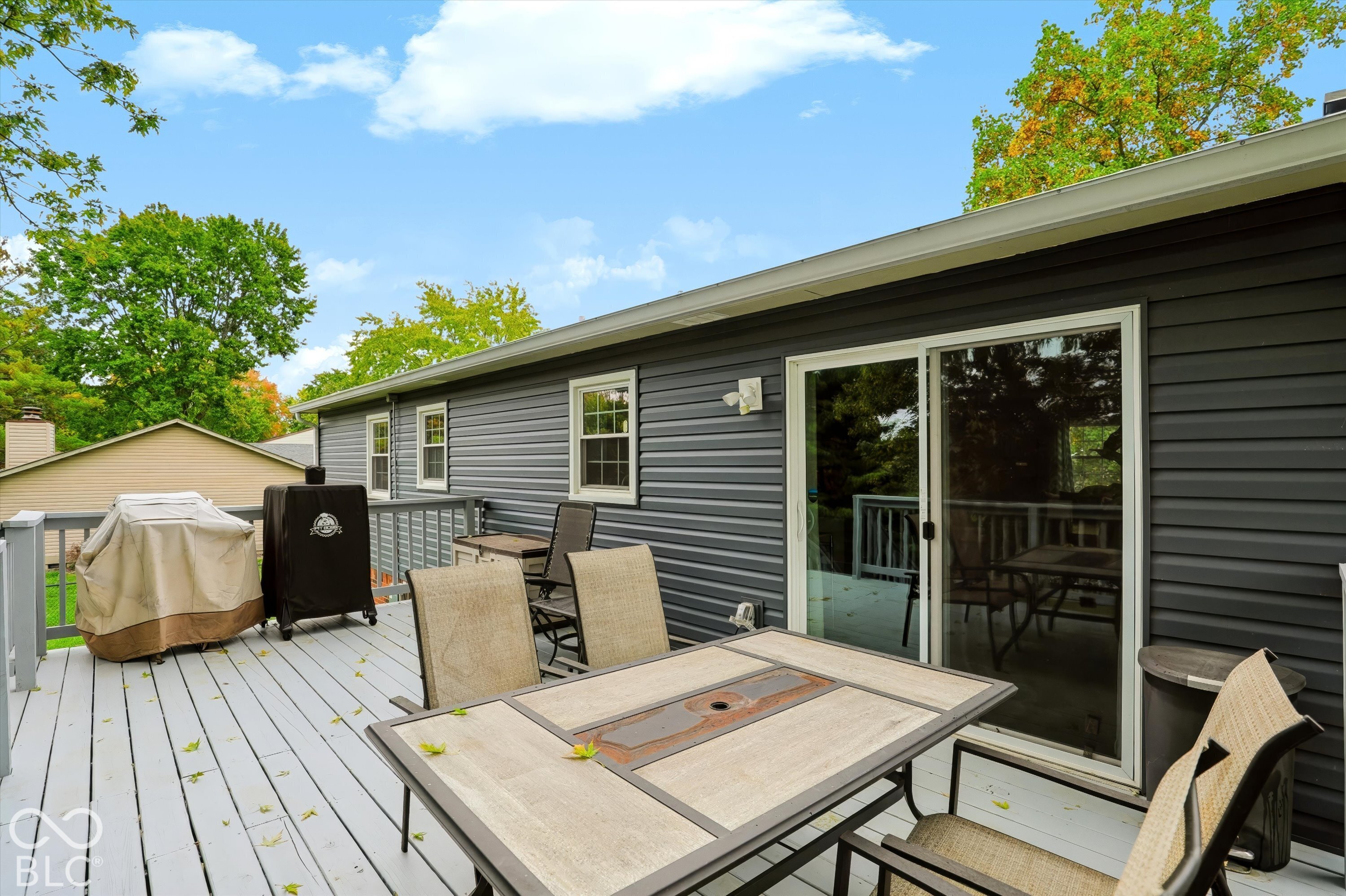 Exterior deck with painted wood-finish surface, dark horizontal siding, and sliding glass door entry
