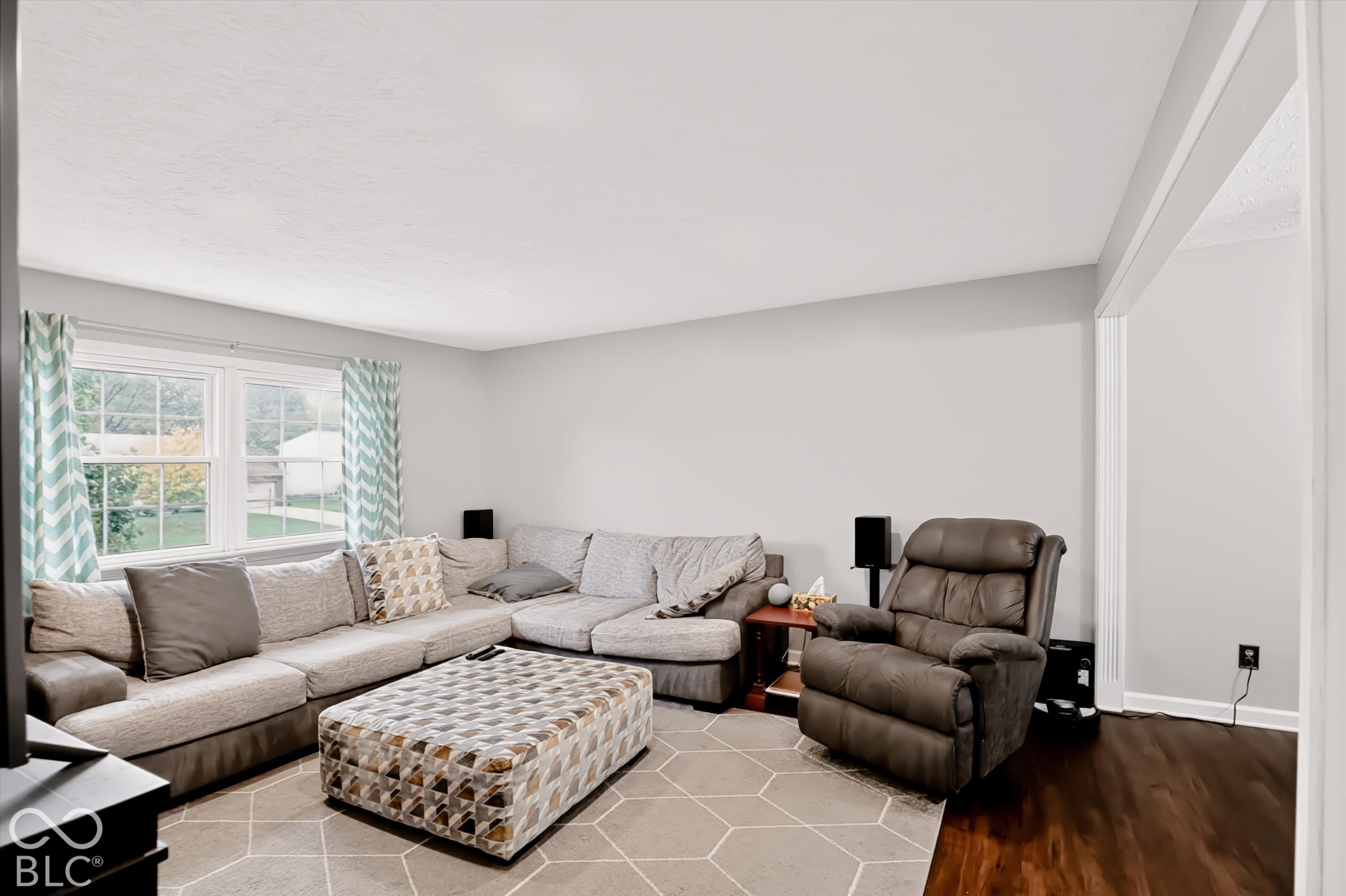 Neutral-toned interior space featuring wood-finish flooring, crisp white walls, and a multi-pane window with white trim