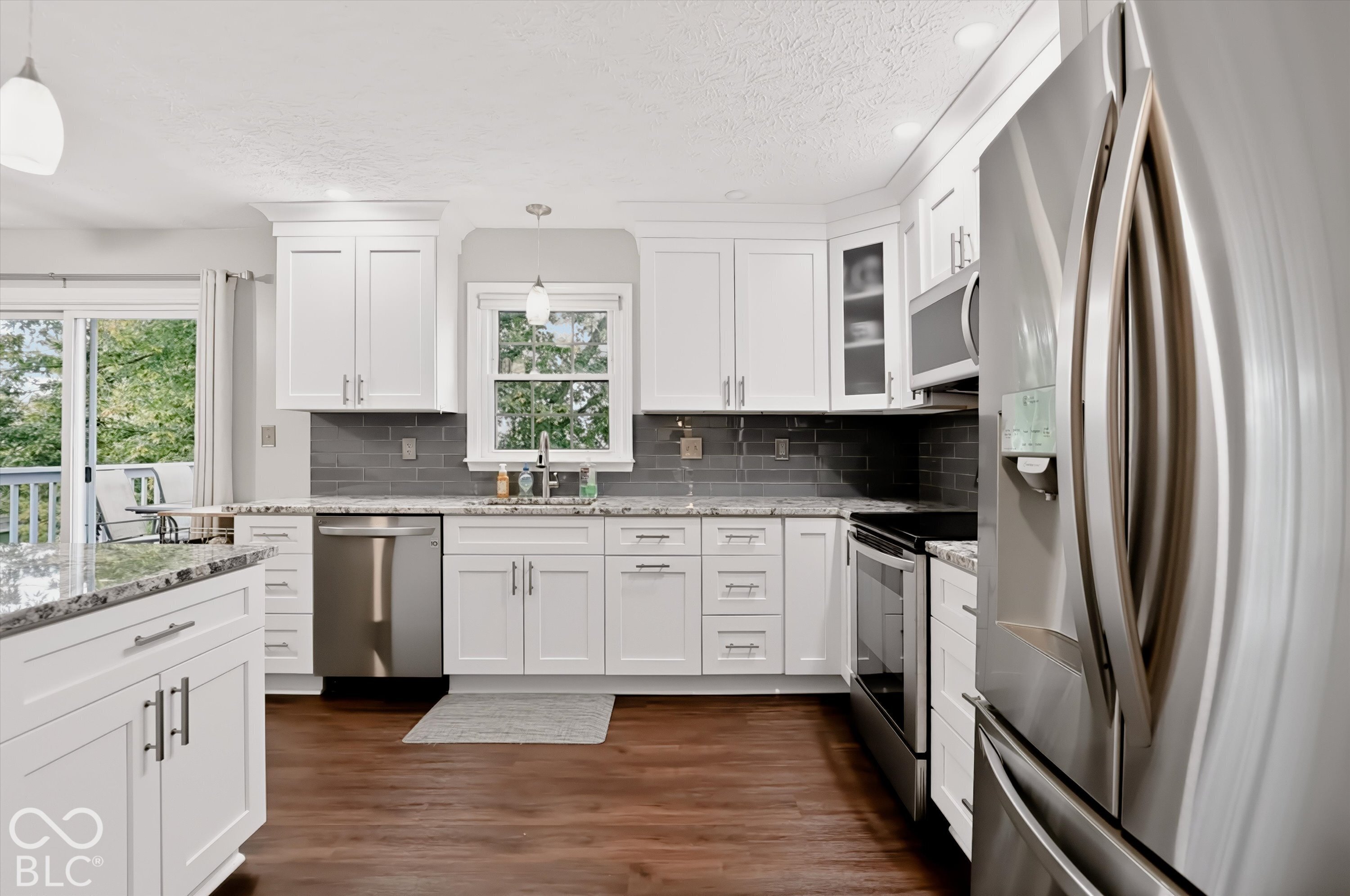 Kitchen featuring white cabinetry, stone-surface countertops, a dark tile backsplash, stainless steel appliances, and wood-finish flooring