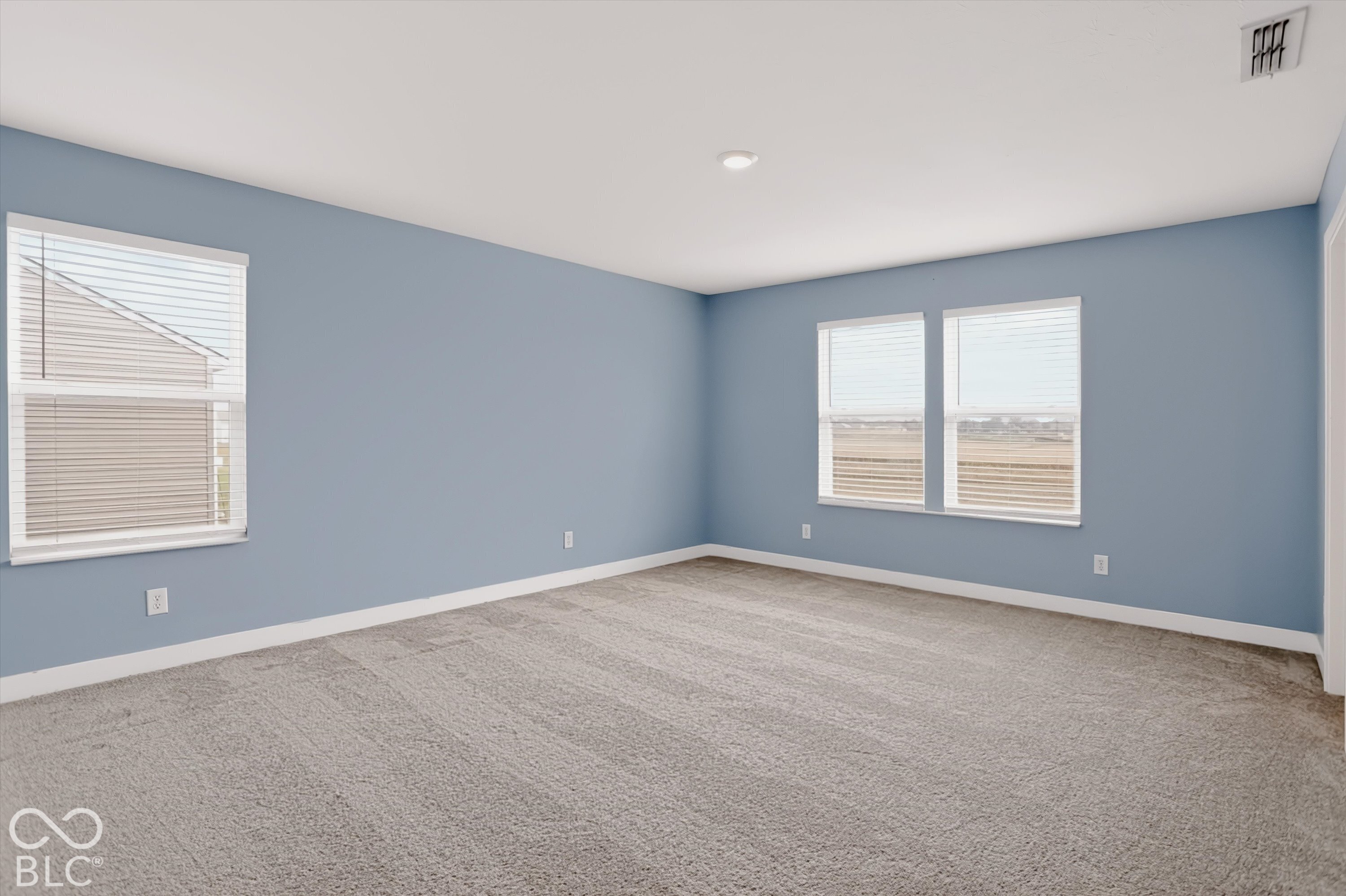 Neutral-toned wall-to-wall carpeting, three double-pane windows, and recessed ceiling lighting