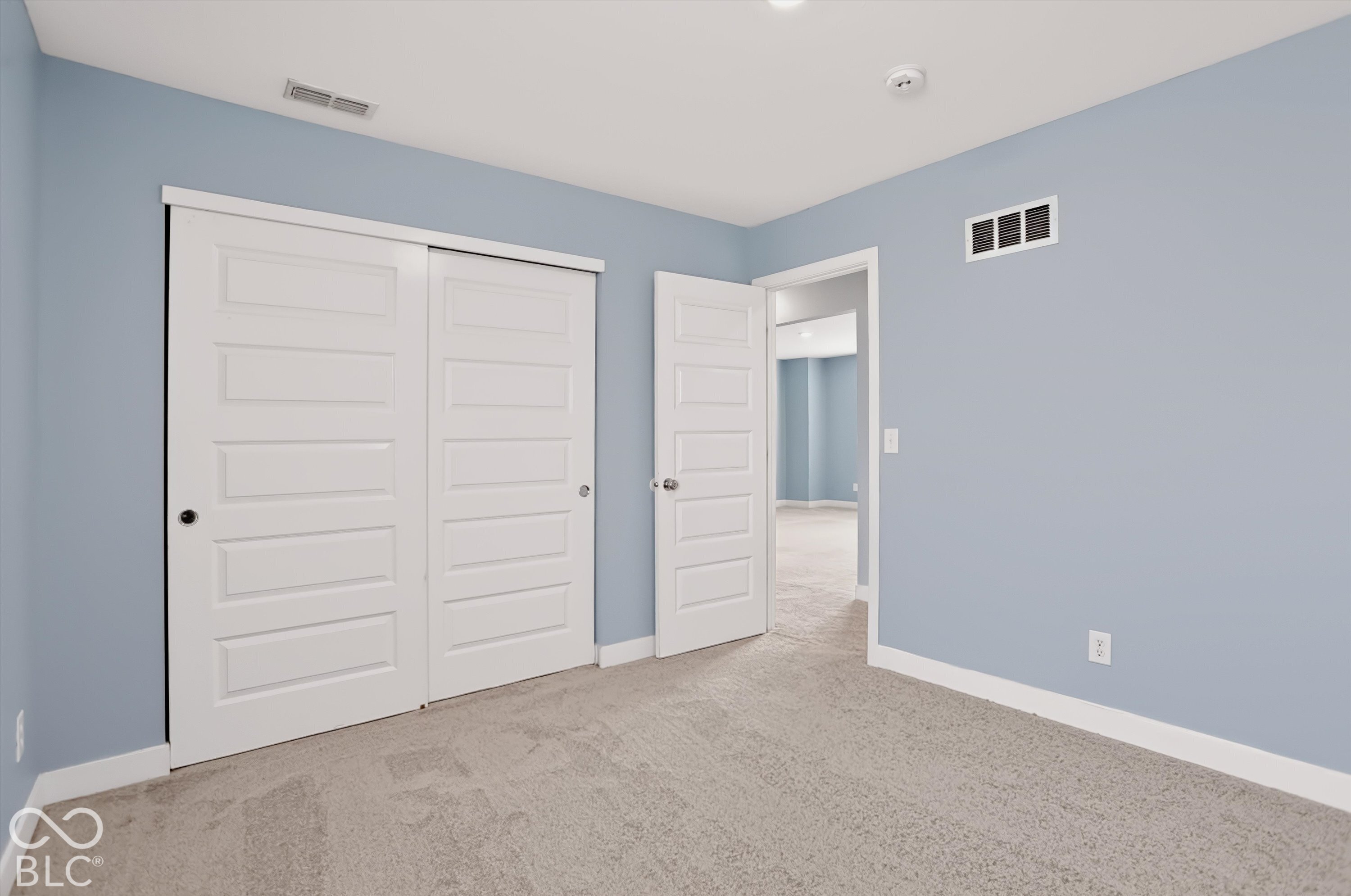 Neutral-toned wall paint, neutral carpeting, sliding bypass closet doors, and six-panel interior doors