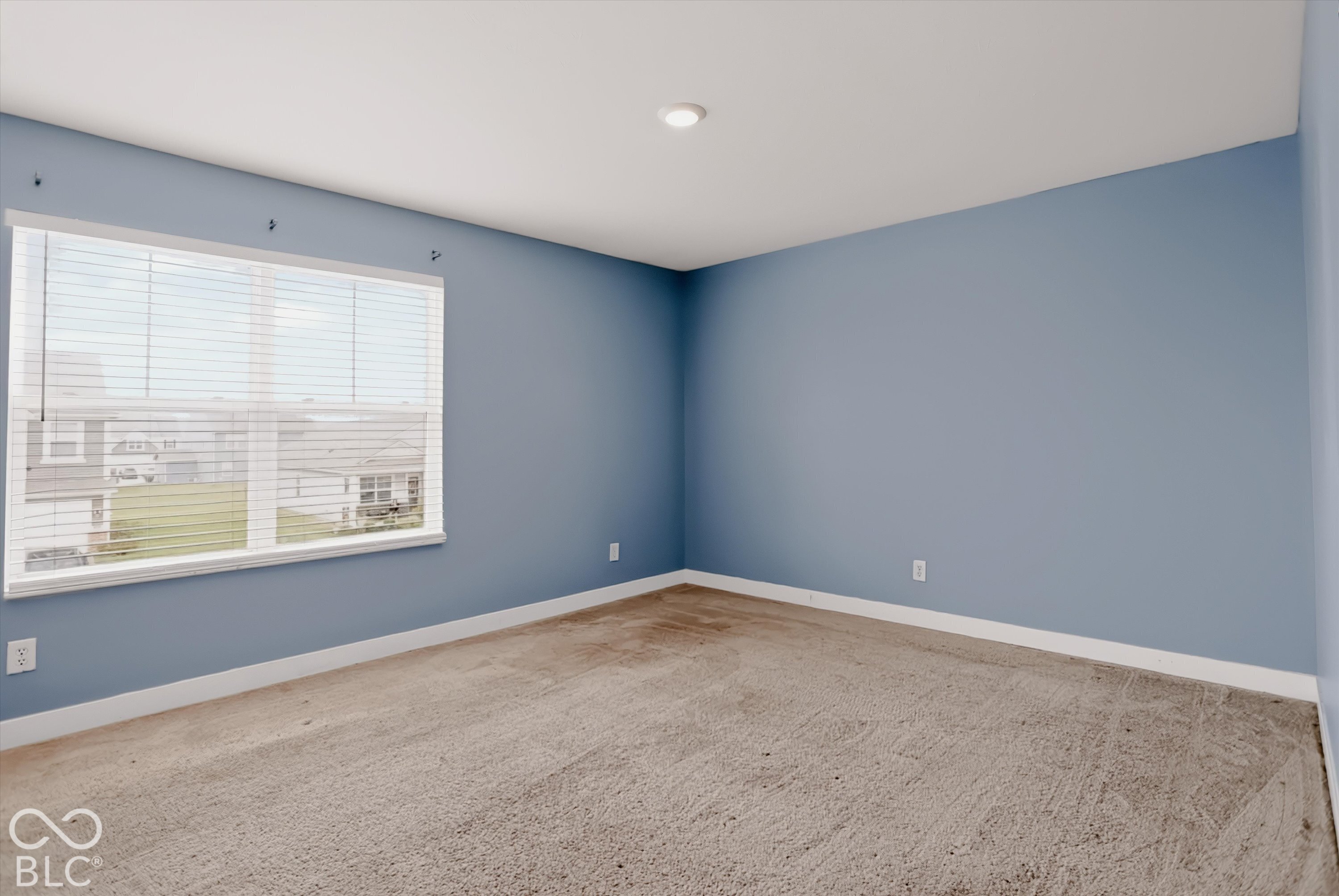 Neutral-toned carpeting, large window with integrated blinds, and recessed lighting