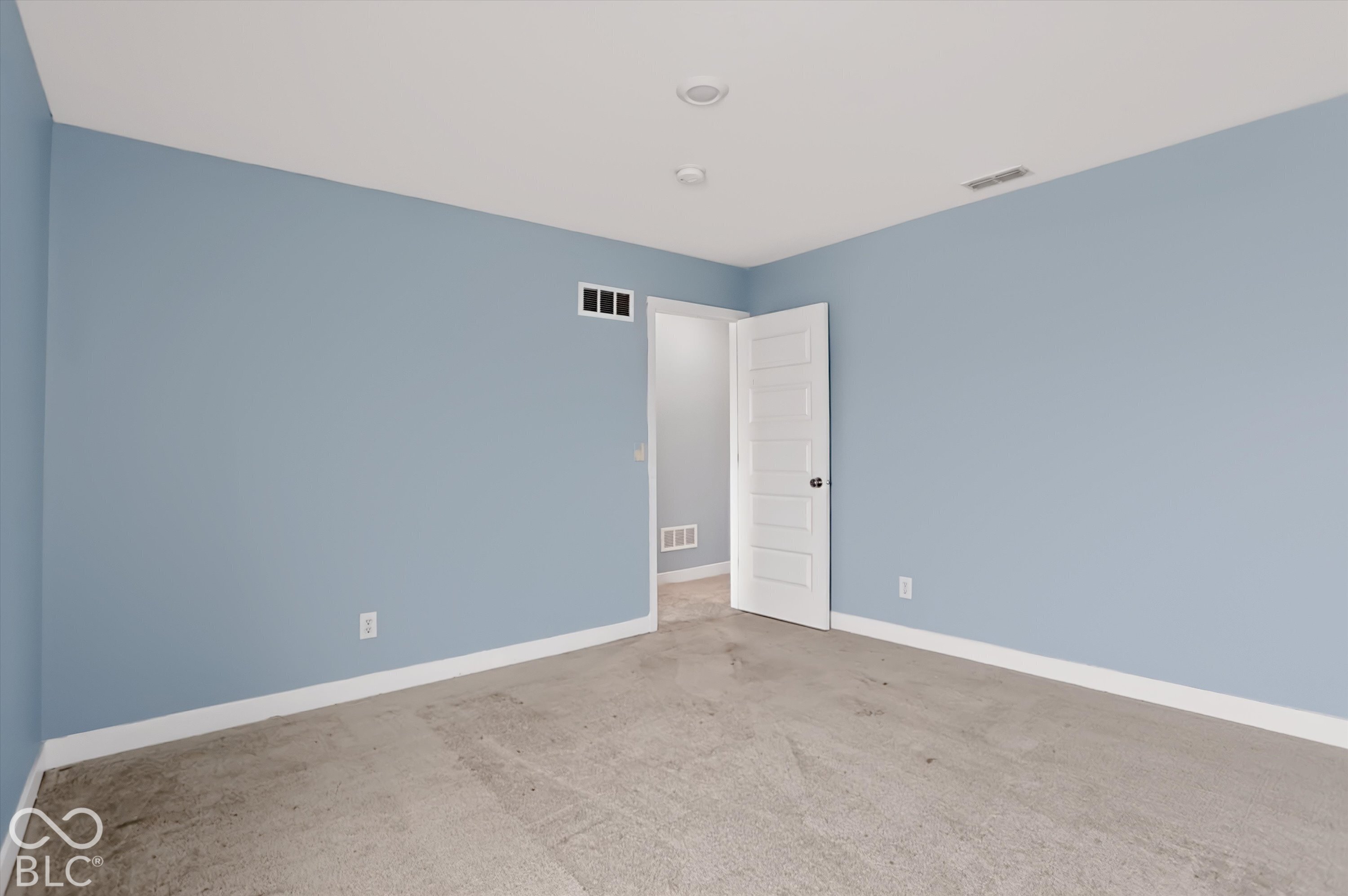 Room featuring neutral carpeting, light blue wall paint, recessed lighting, and a white five-panel interior door