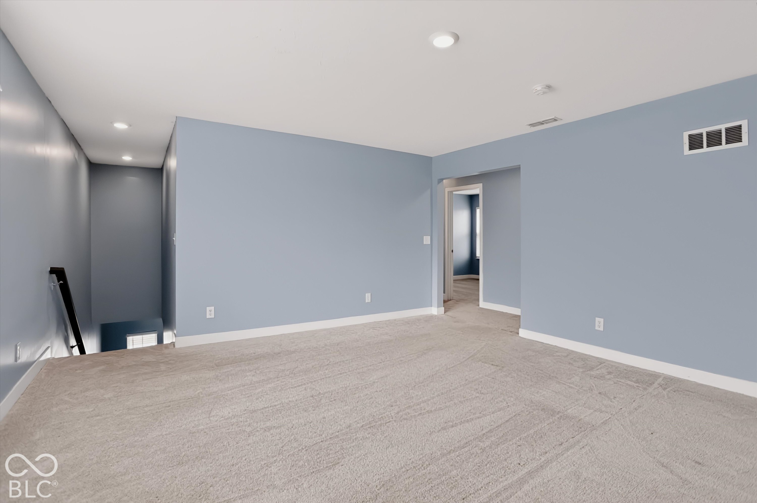 Neutral-toned interior space featuring light-colored wall paint, plush carpeting, and recessed ceiling lighting