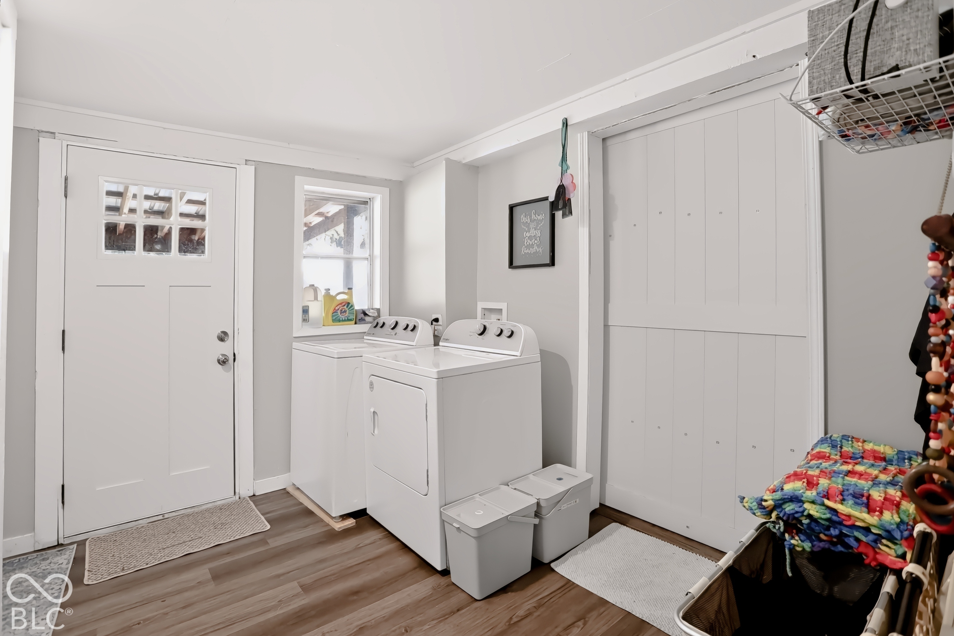 Wood-finish flooring with a white paneled door, a single window, and a white sliding barn door
