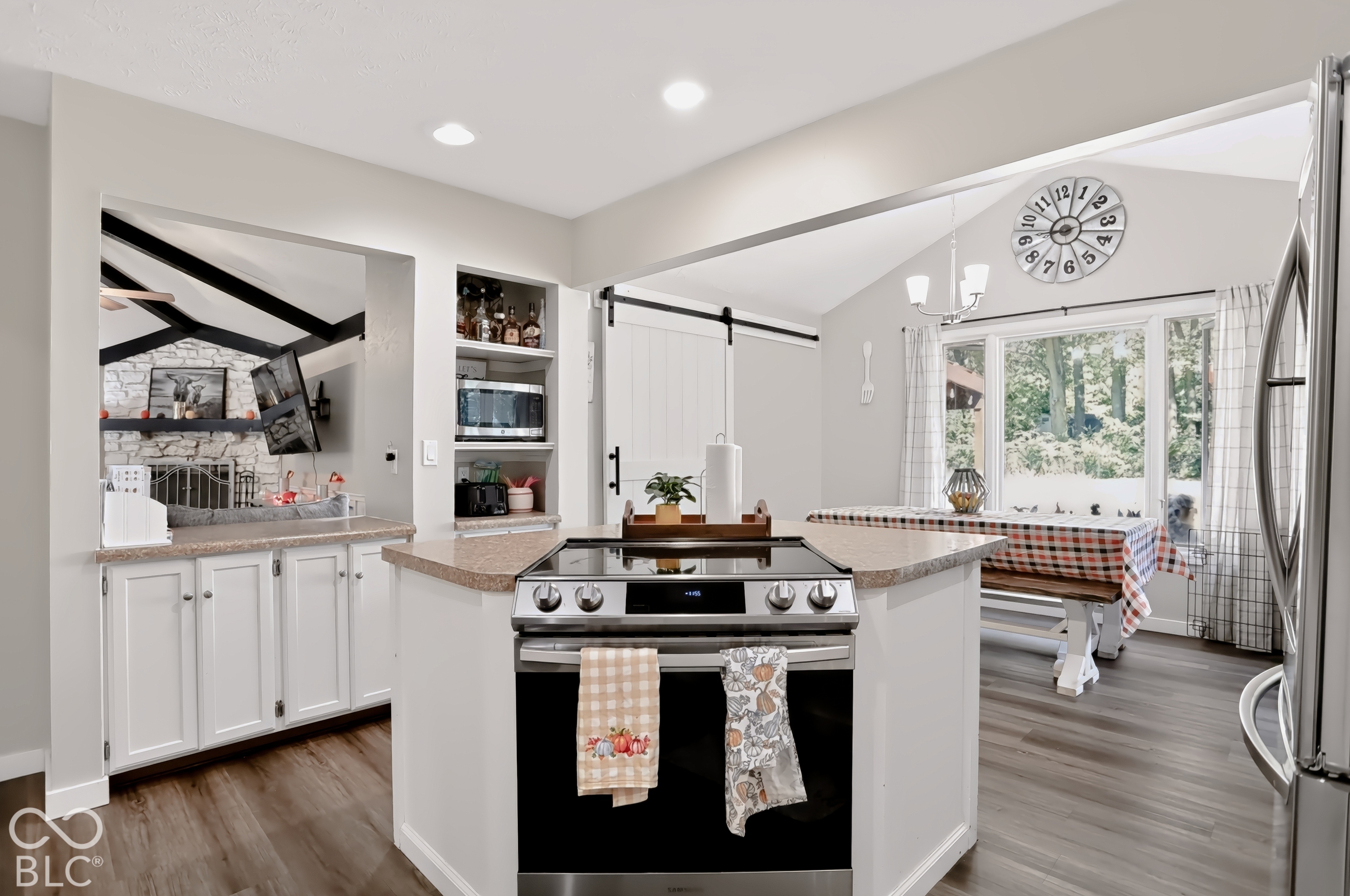 Kitchen featuring a center island with built-in range, wood-finish flooring, white cabinetry, and built-in shelving