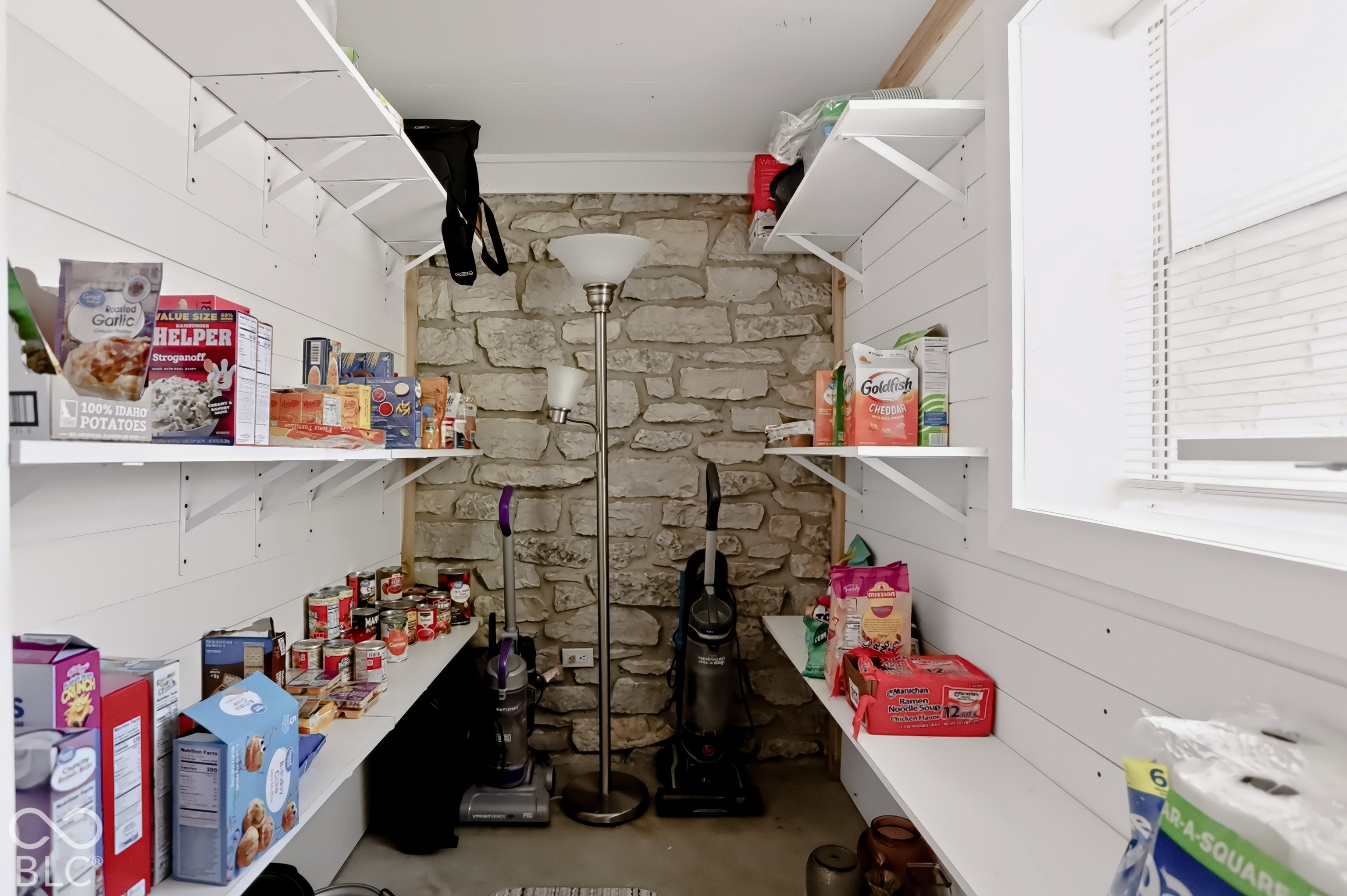 Built-in shelving, stone accent wall, window with blinds, white shiplap walls, and recessed lighting
