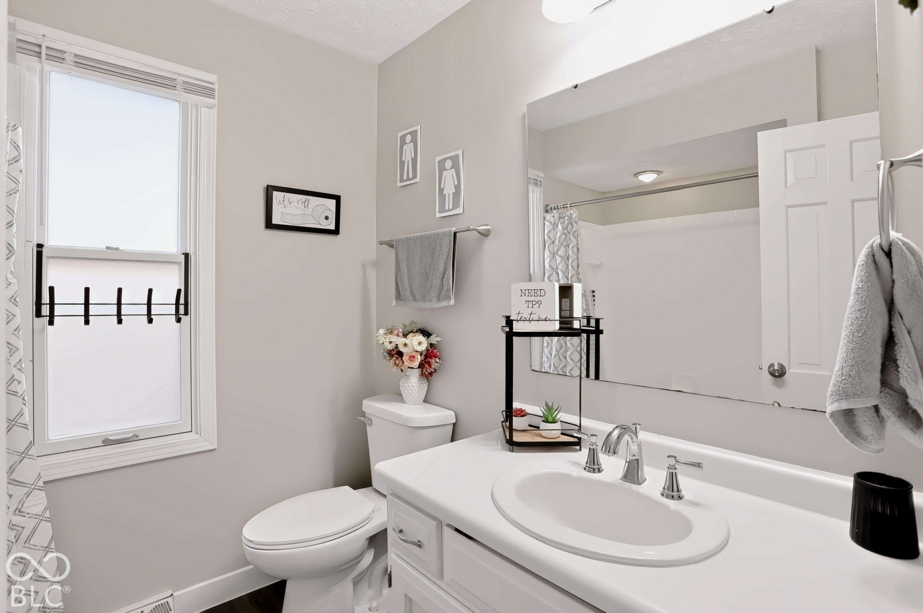 White vanity with integrated sink, polished chrome faucet, and expansive wall mirror