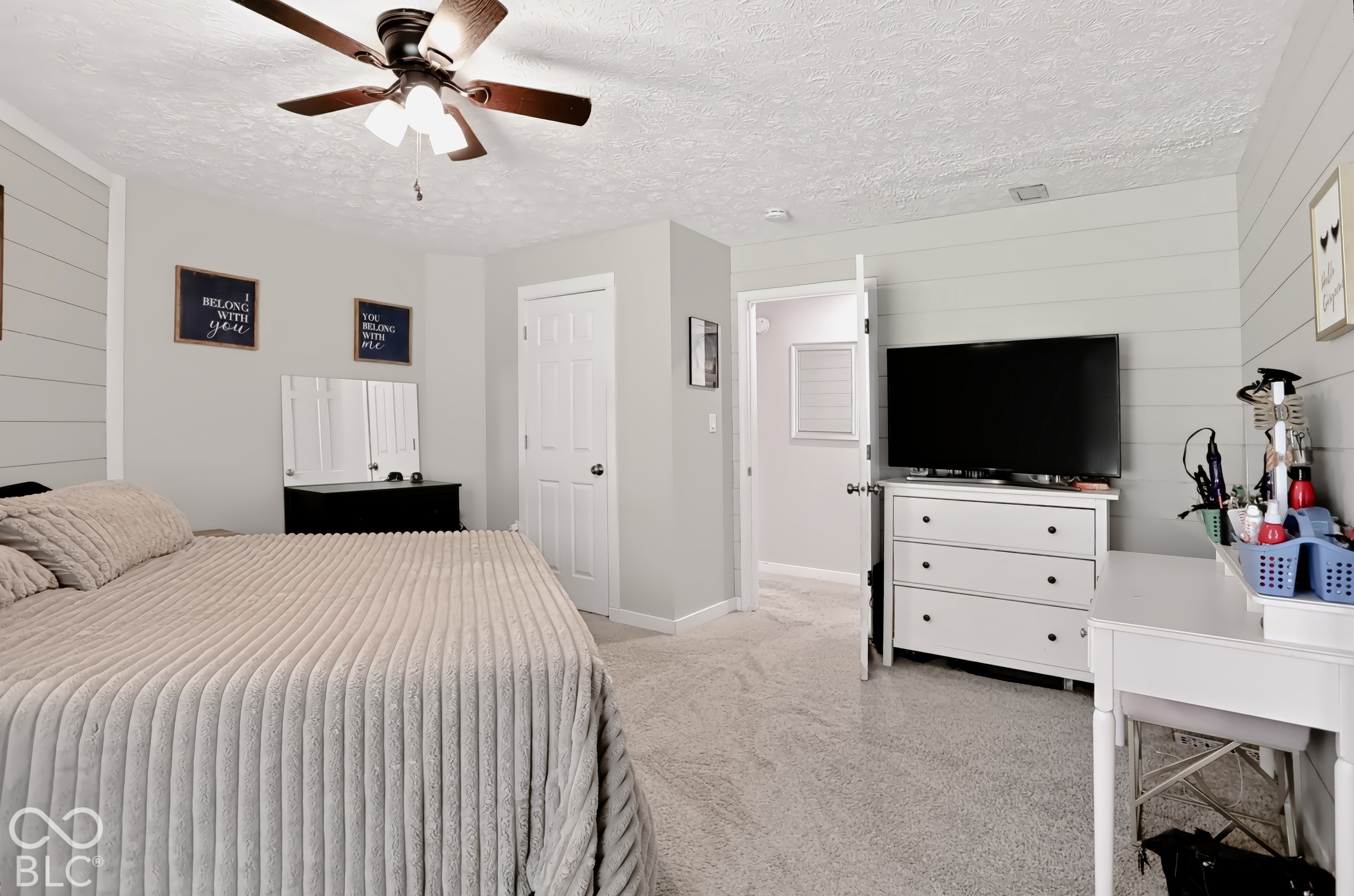 Carpet flooring, ceiling fan with integrated lighting, paneled accent wall, and a white interior door