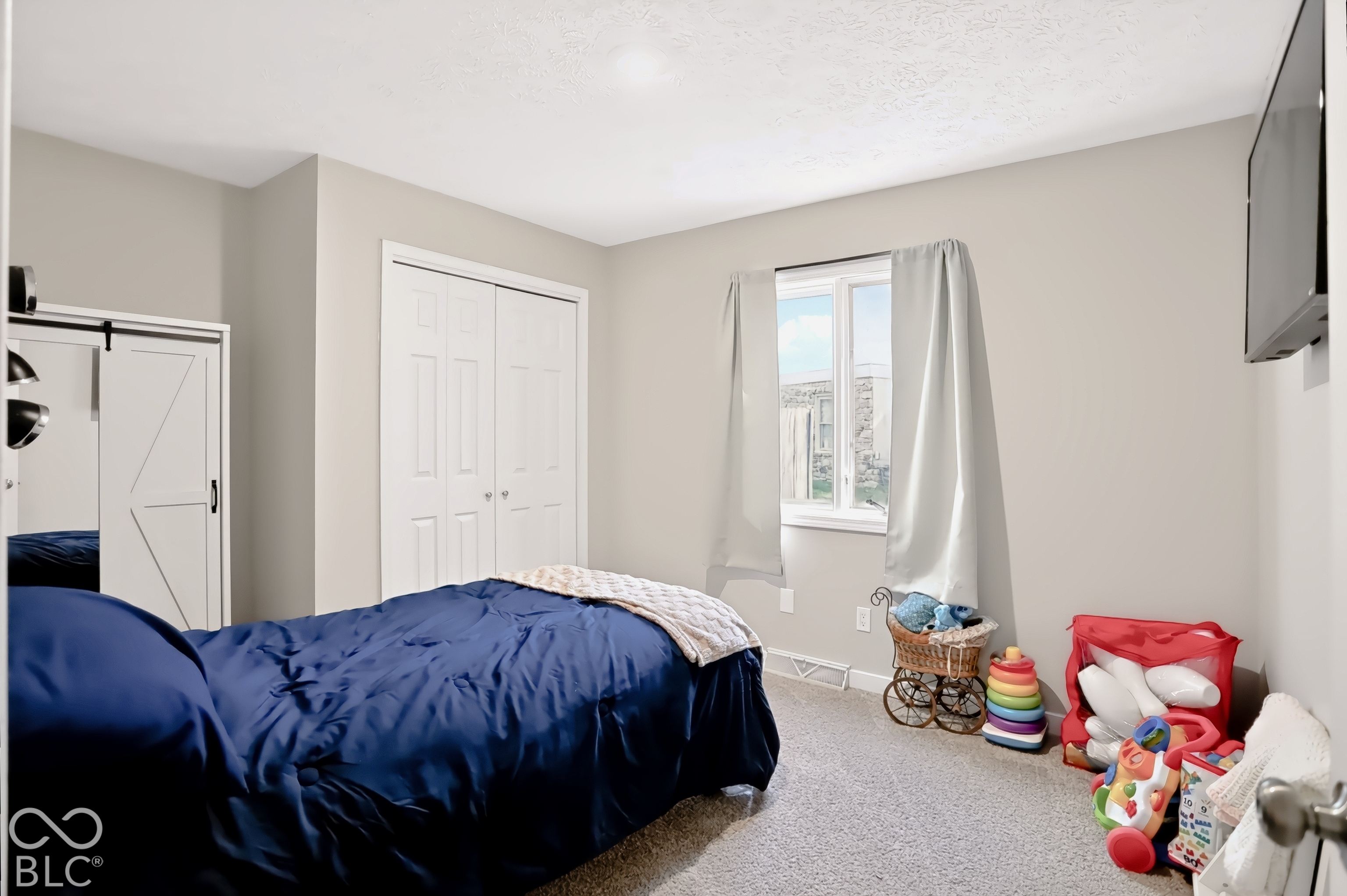 White bi-fold closet doors, a single window, and neutral wall paint