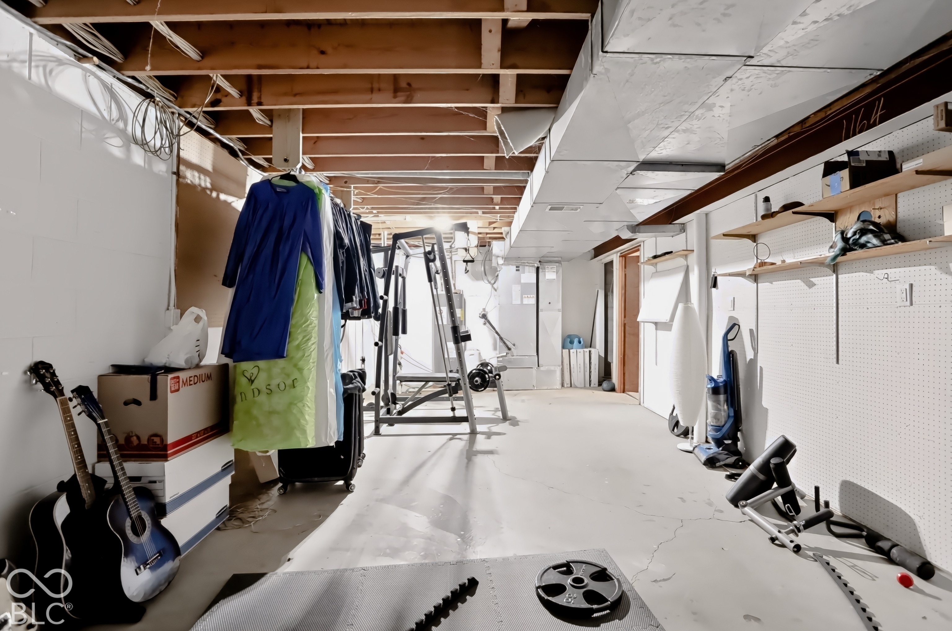 Unfinished basement featuring exposed wood beams, concrete flooring, white painted walls, and overhead ductwork