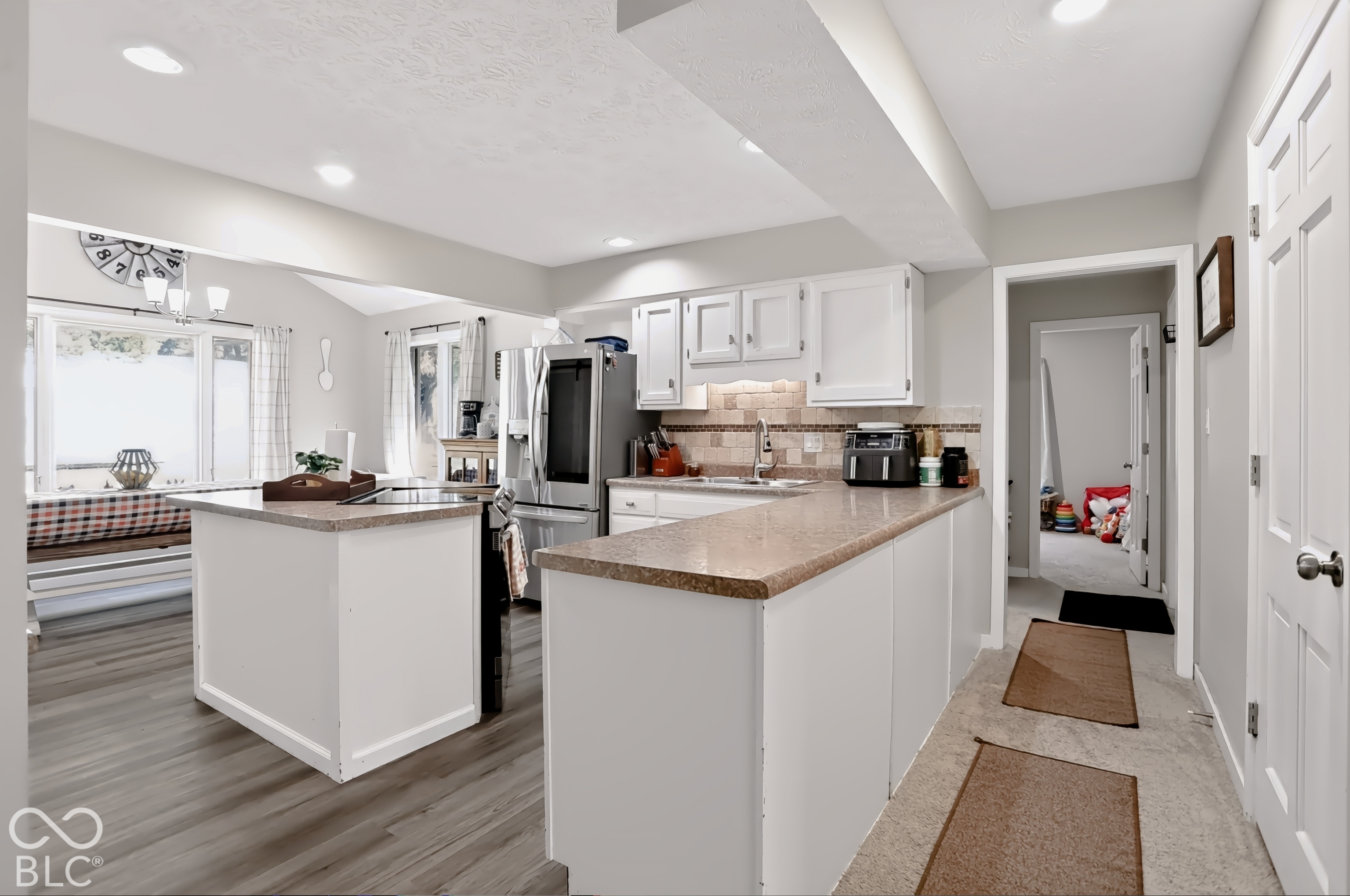 White cabinetry with stone countertops, stainless steel appliances, wood-finish flooring, and recessed lighting