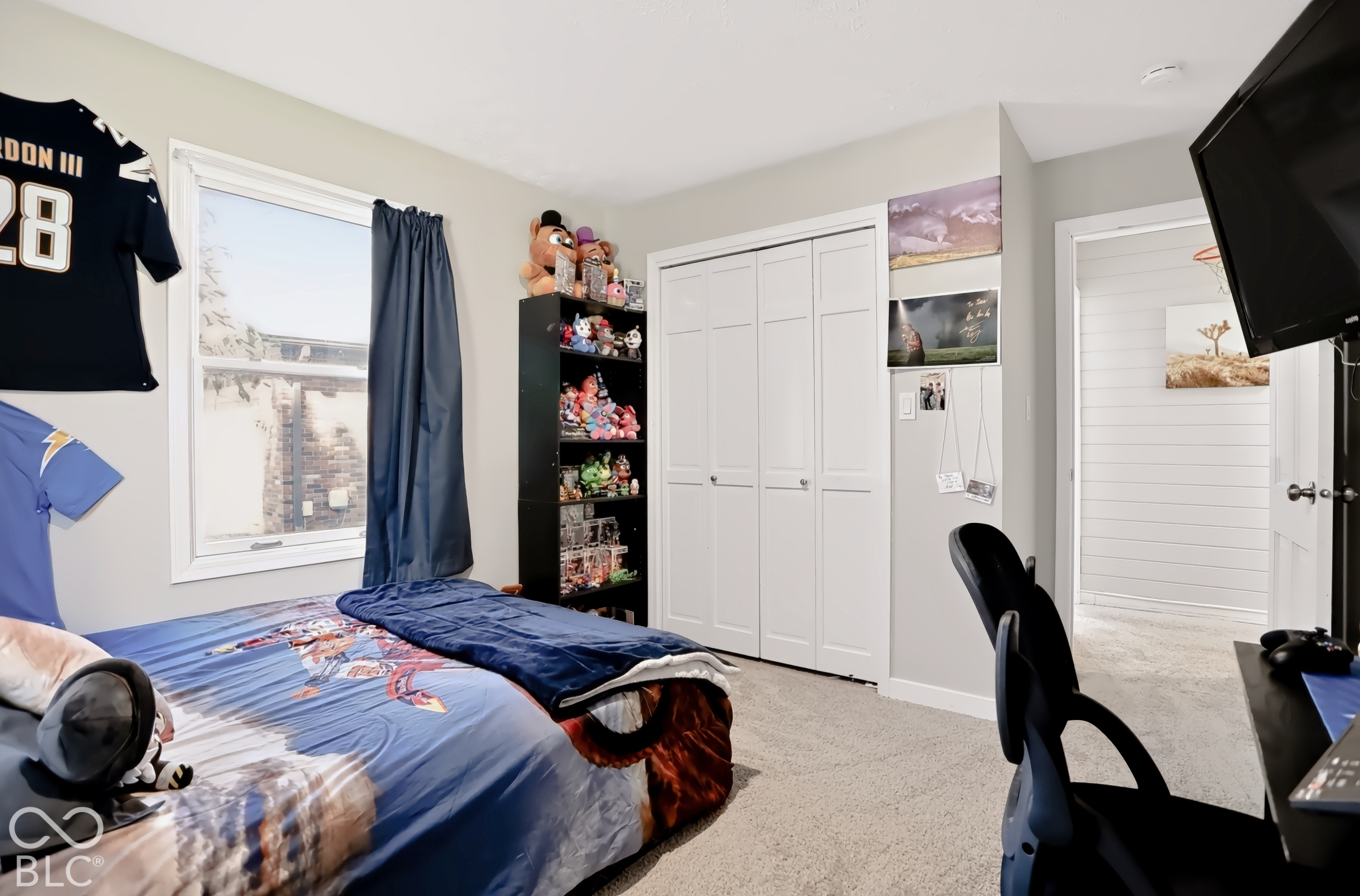 Light-toned wall paint, neutral carpeting, and a white framed window with an adjacent closet featuring bi-fold doors