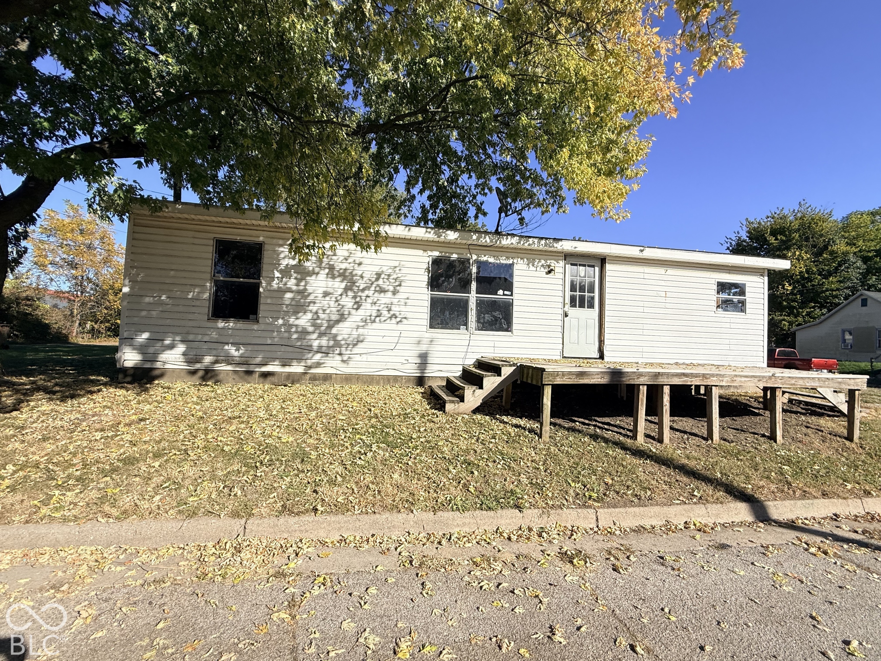 Exterior featuring white siding, a raised wood-finish deck with steps, and multiple windows Exterior featuring white siding, a raised wood-finish deck with steps, and multiple windows