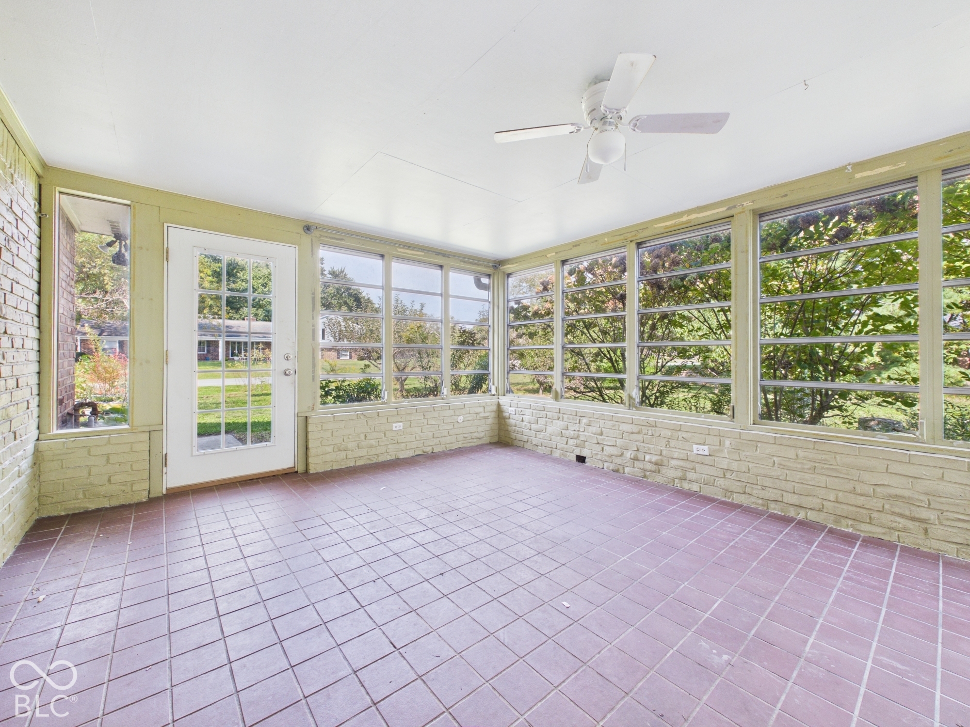Sunroom with brick half-walls, extensive window coverage, and tile flooring