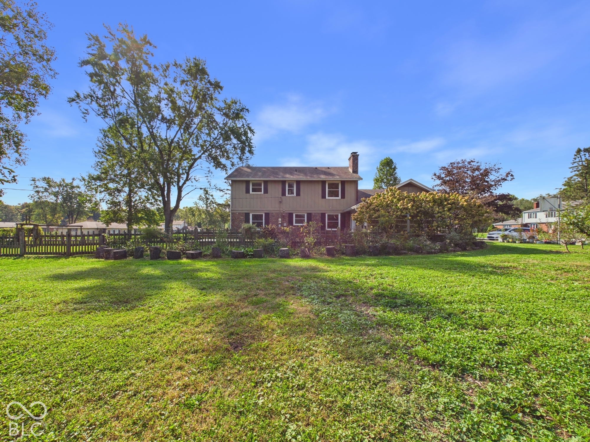 Expansive green lawn with a privacy fence and mature trees