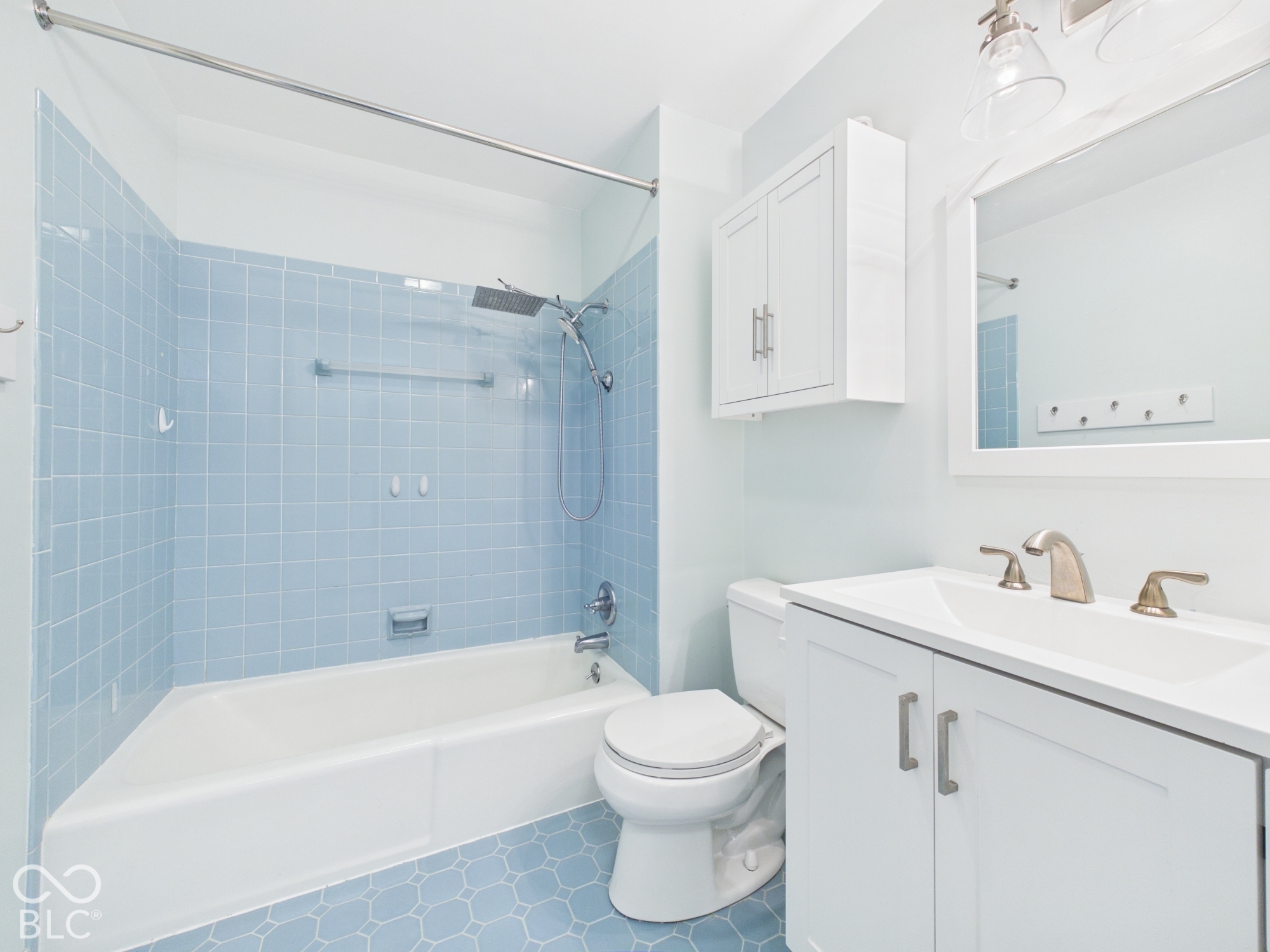Bathroom featuring a white vanity with integrated sink, a built-in bathtub, and blue tiled walls