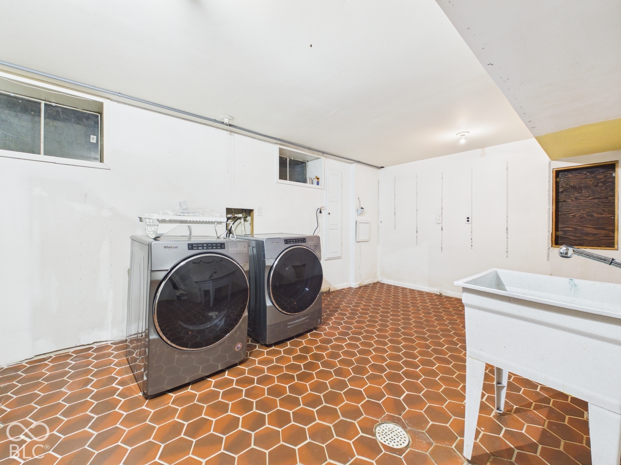 Laundry area featuring hexagonal tile flooring, a utility sink, and built-in washing machine and dryer