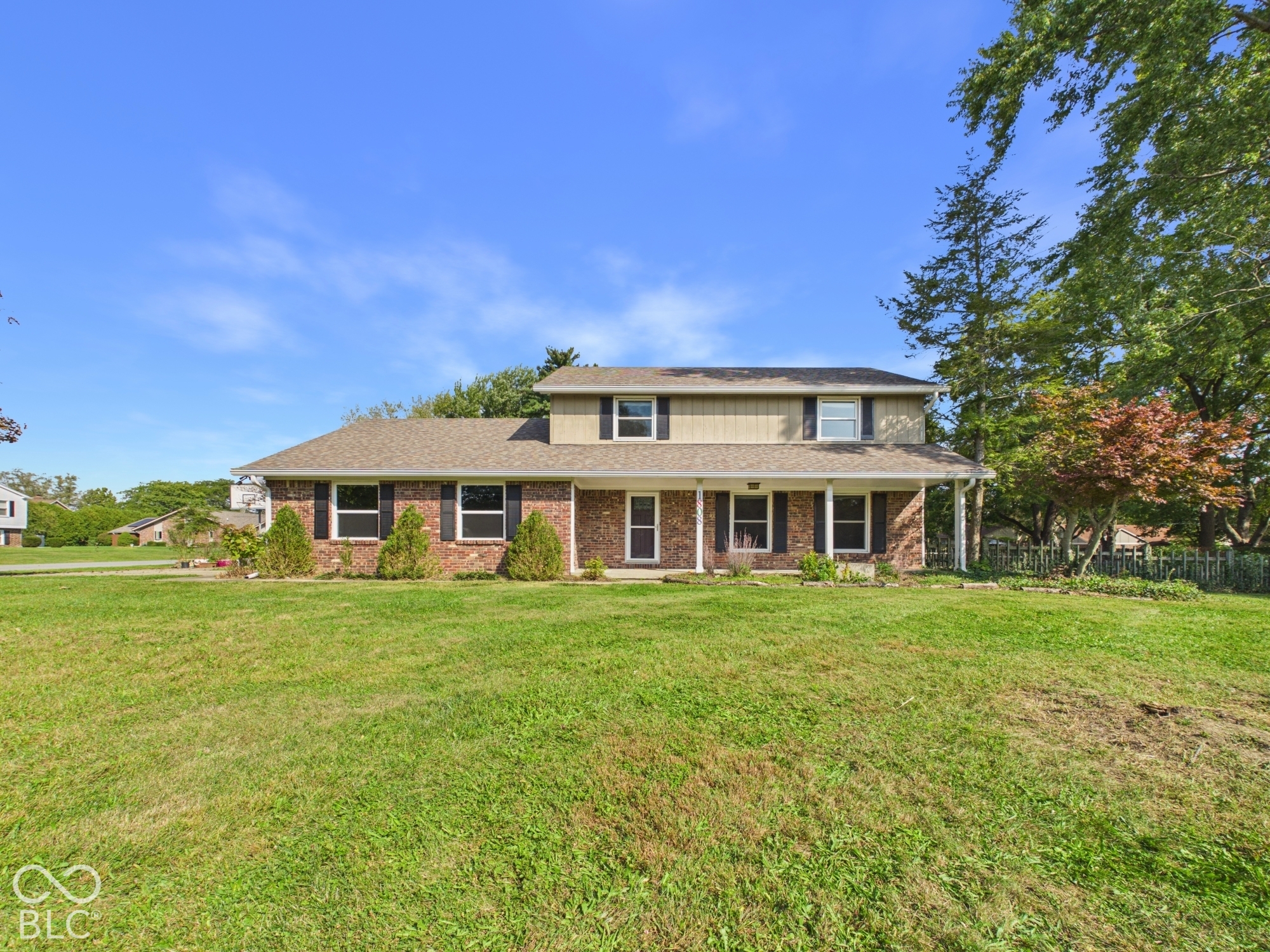 Two-story residence featuring a brick and siding exterior, a covered porch with white columns, and a shingled roof