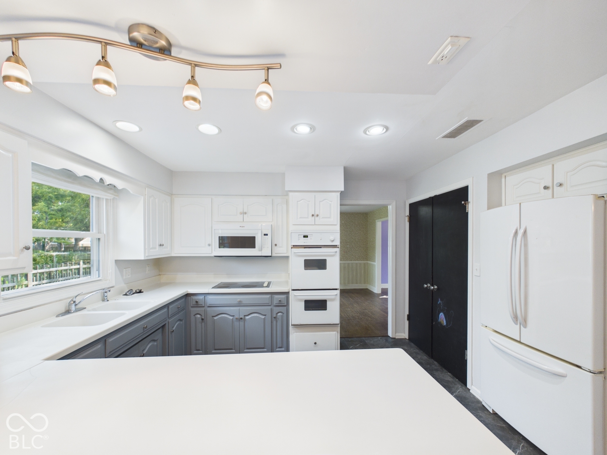 Kitchen featuring recessed lighting, a track lighting fixture, white upper cabinetry, gray lower cabinetry, and an integrated double oven