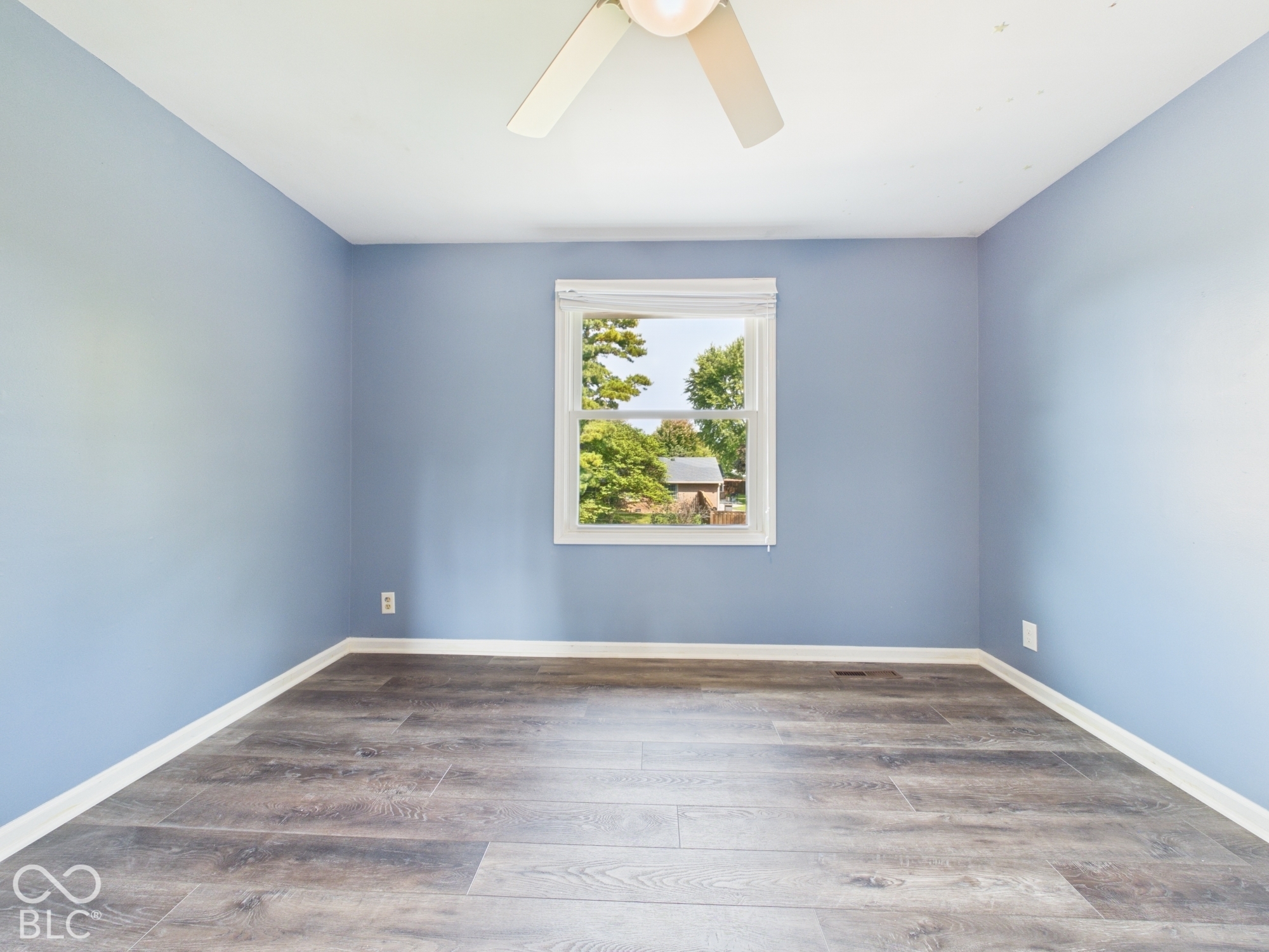 Wood-finish flooring, light blue walls, and a white window frame with blinds