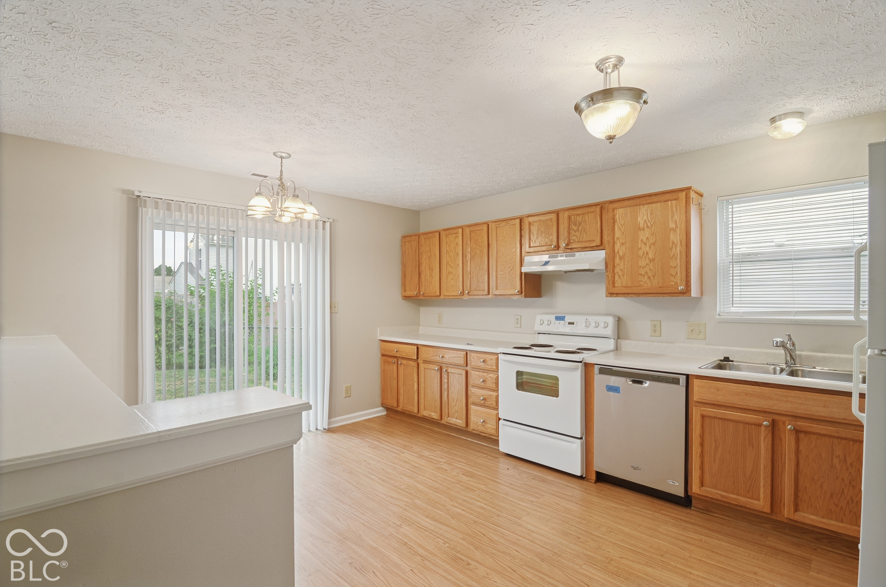 Kitchen featuring wood cabinetry, wood-finish flooring, sliding glass patio door, and stainless steel dishwasher