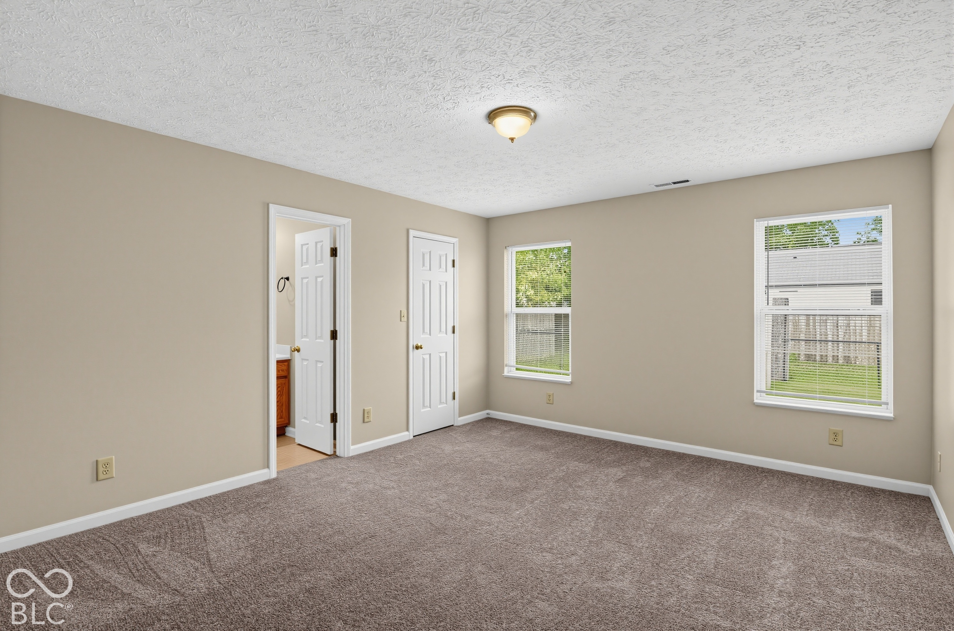 Neutral-toned interior space featuring neutral carpeting, double-hung windows, and white six-panel interior doors