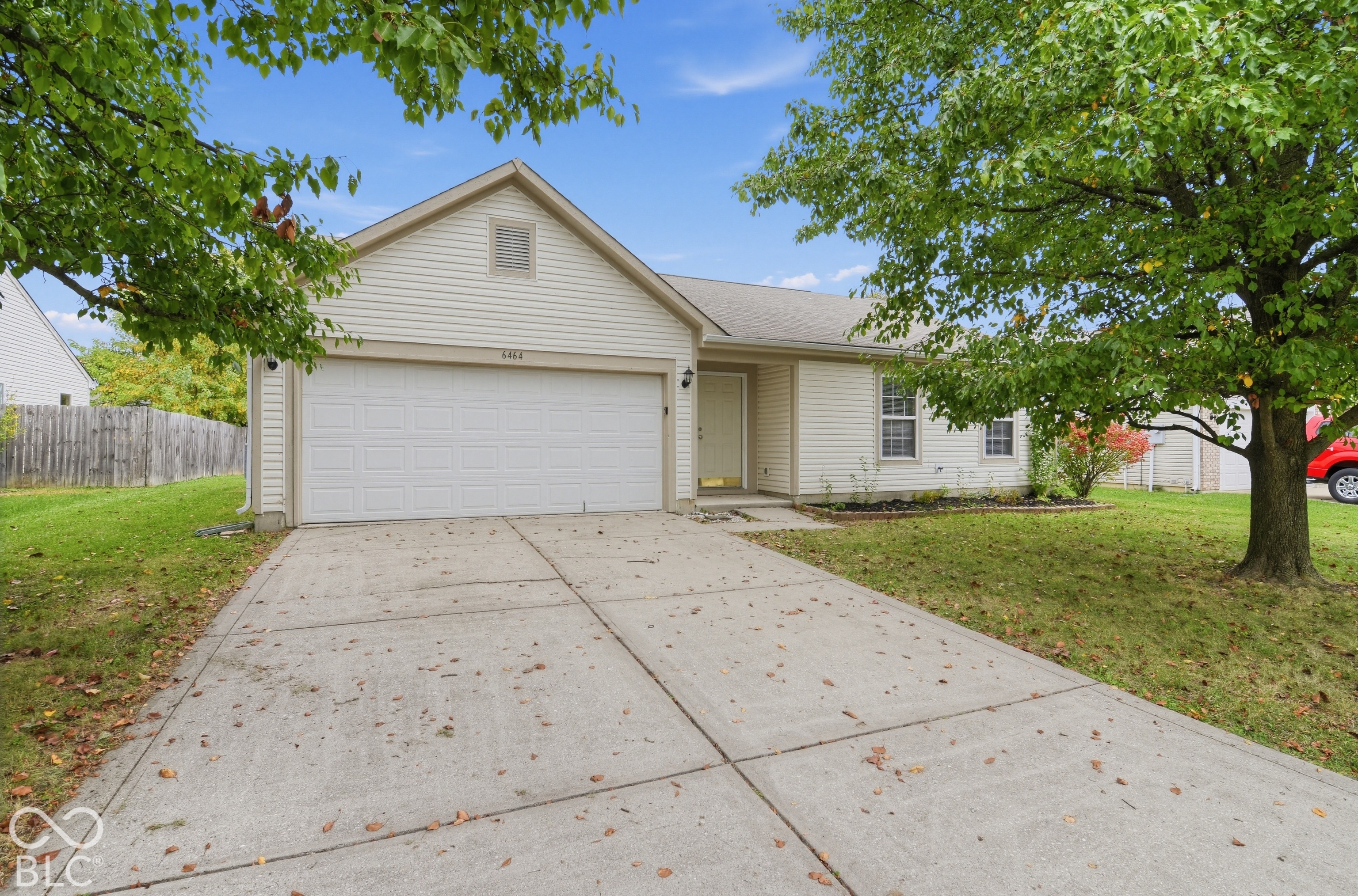 Single-story exterior featuring light-colored horizontal siding, a two-car attached garage, a concrete driveway, and mature trees Single-story exterior featuring light-colored horizontal siding, a two-car attached garage, a concrete driveway, and mature trees