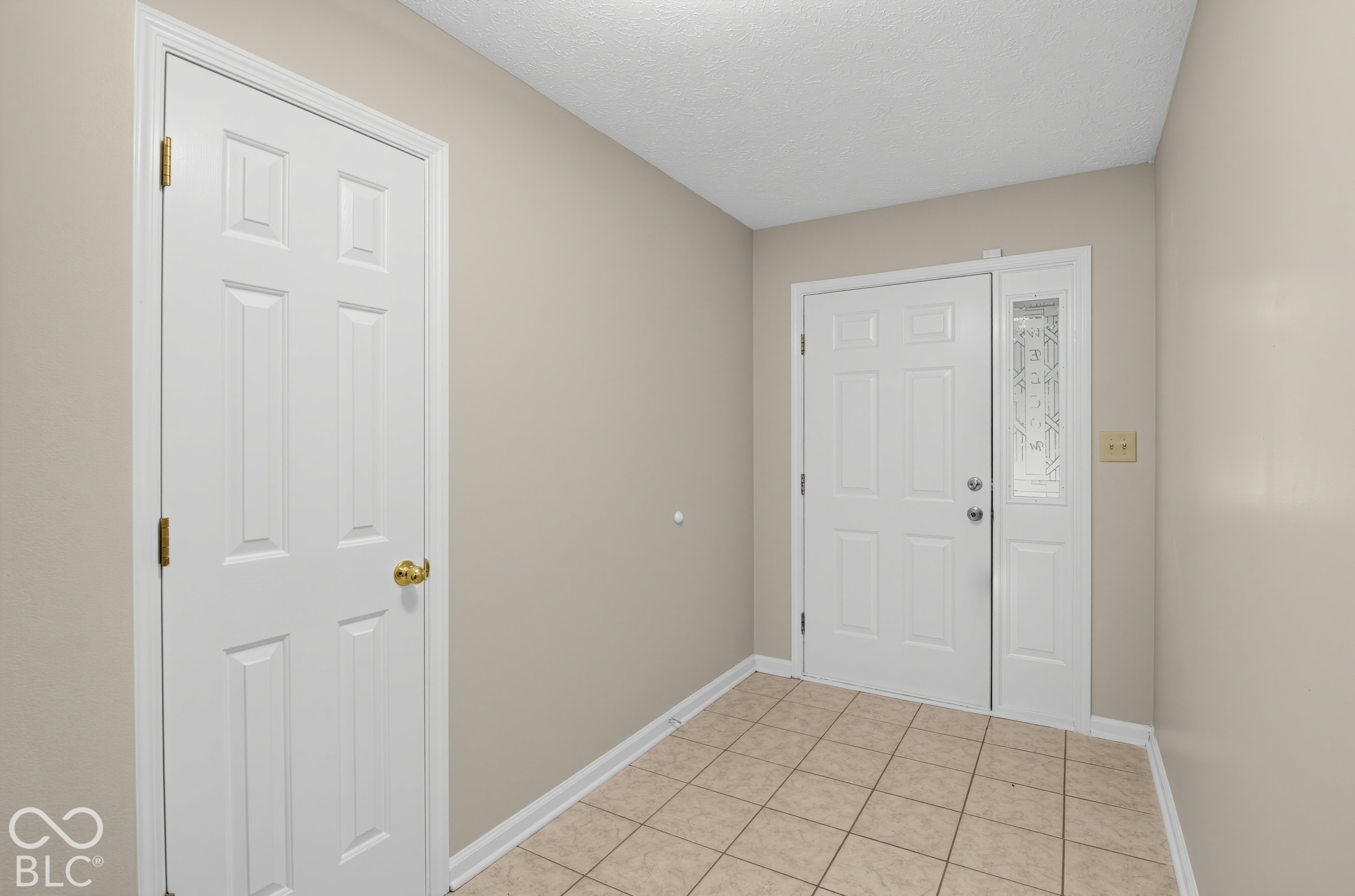 Entryway featuring ceramic tile flooring, a six-panel exterior door with a decorative glass sidelight, and a matching six-panel interior door
