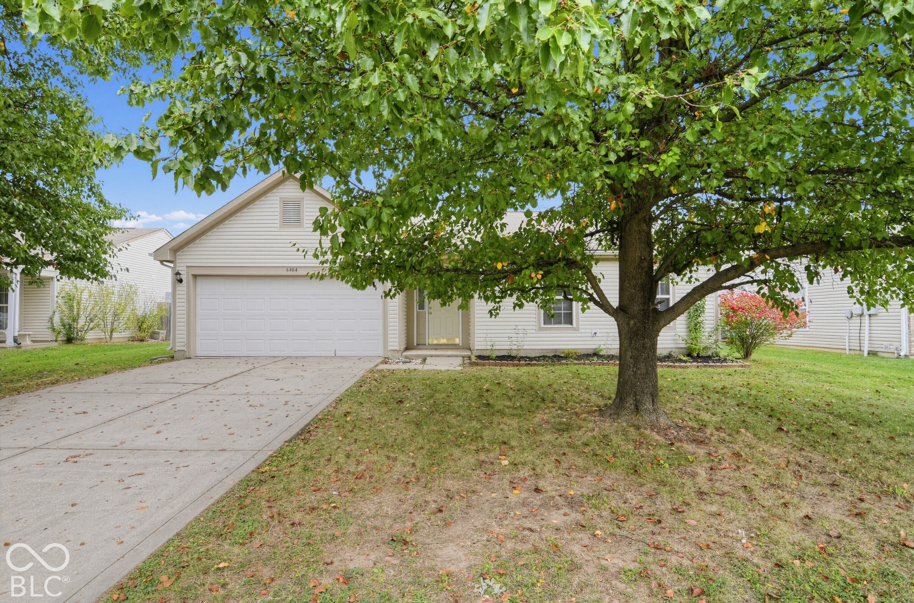 Vinyl siding exterior with a front-facing attached two-car garage, concrete driveway, and mature landscaping