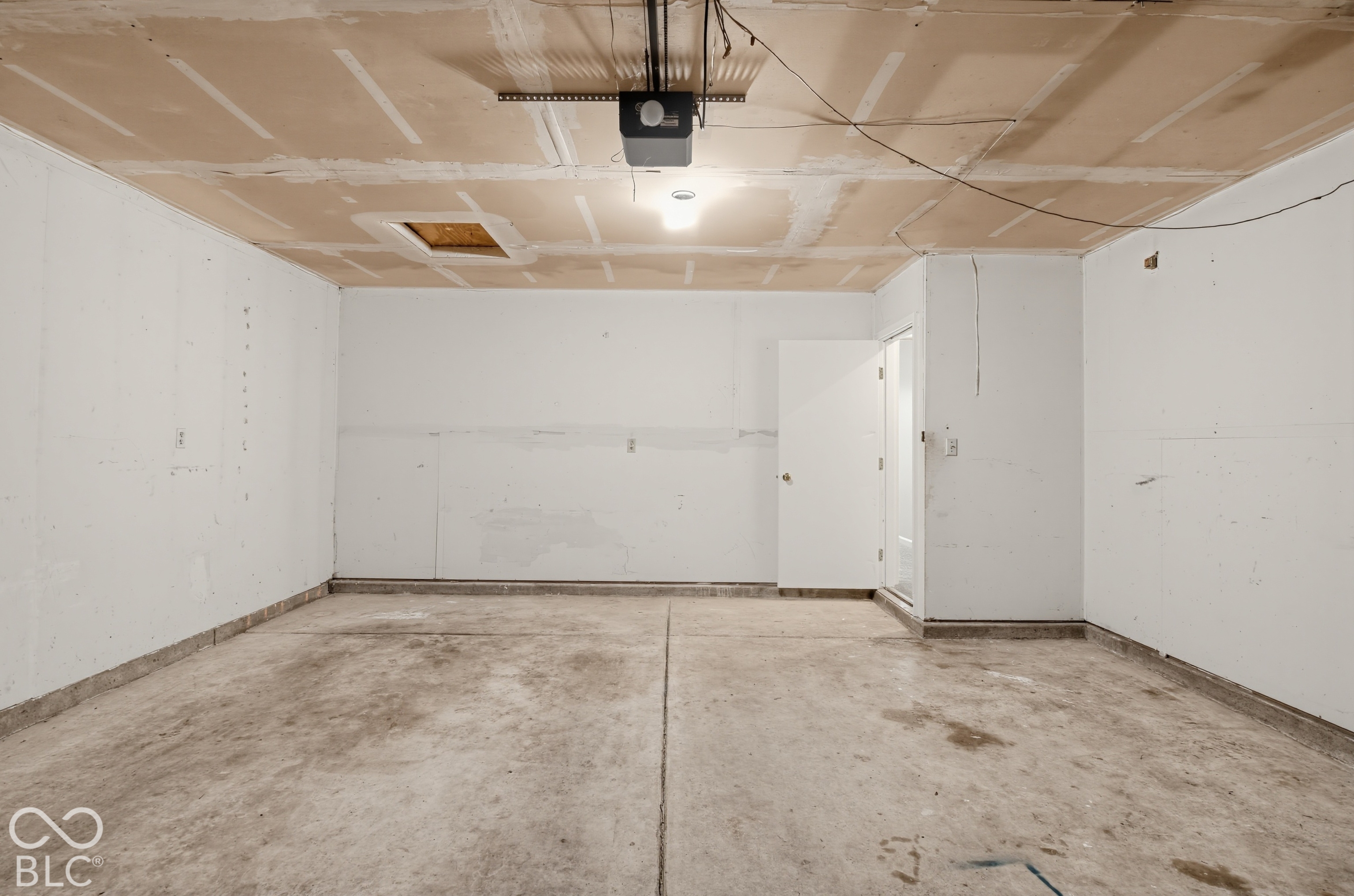 Enclosed garage space featuring a concrete floor, painted drywall, and an overhead automatic garage door opener