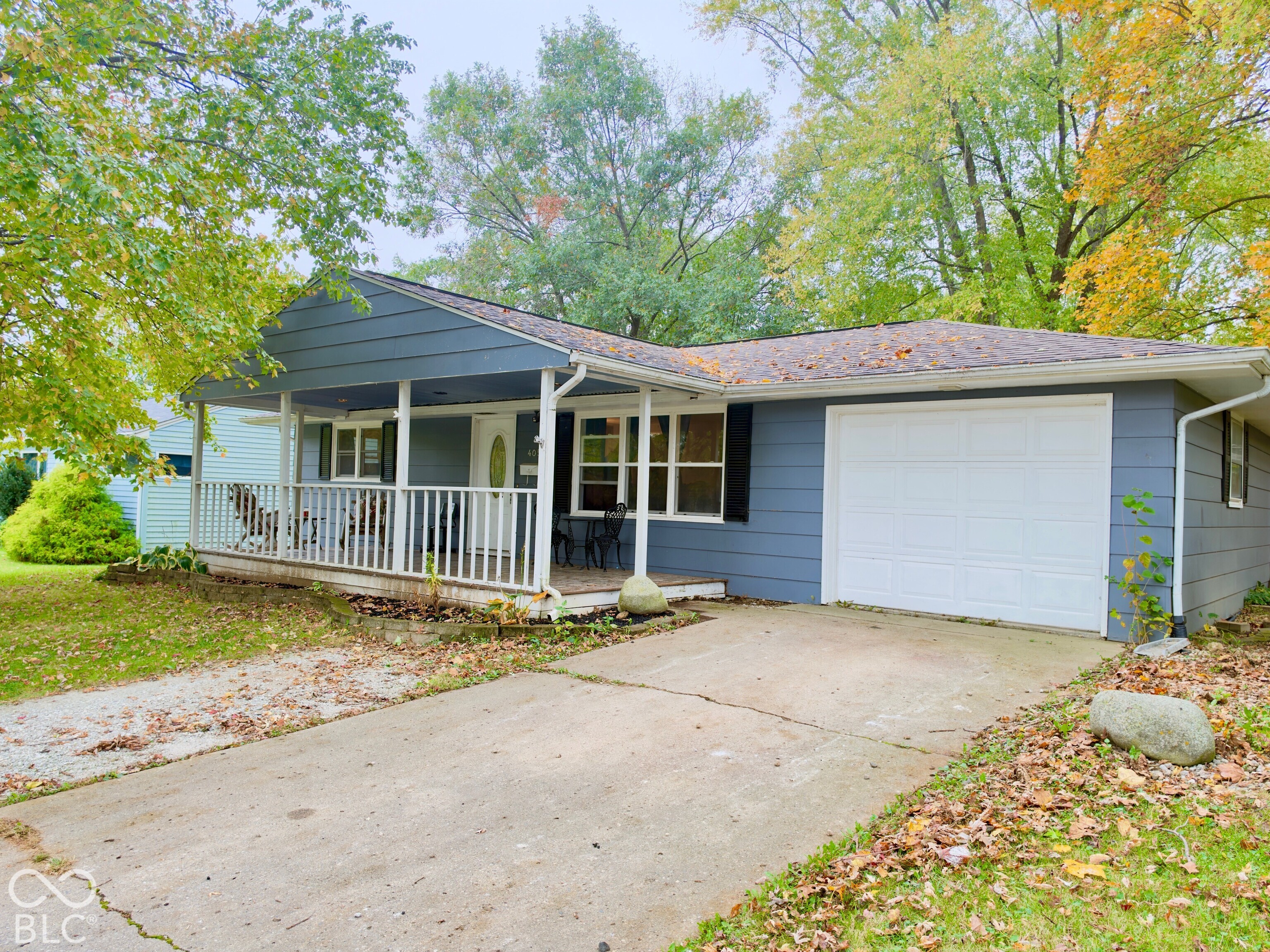 Single-story residence featuring horizontal lap siding, a covered front porch with white railing, and a single-car garage Single-story residence featuring horizontal lap siding, a covered front porch with white railing, and a single-car garage