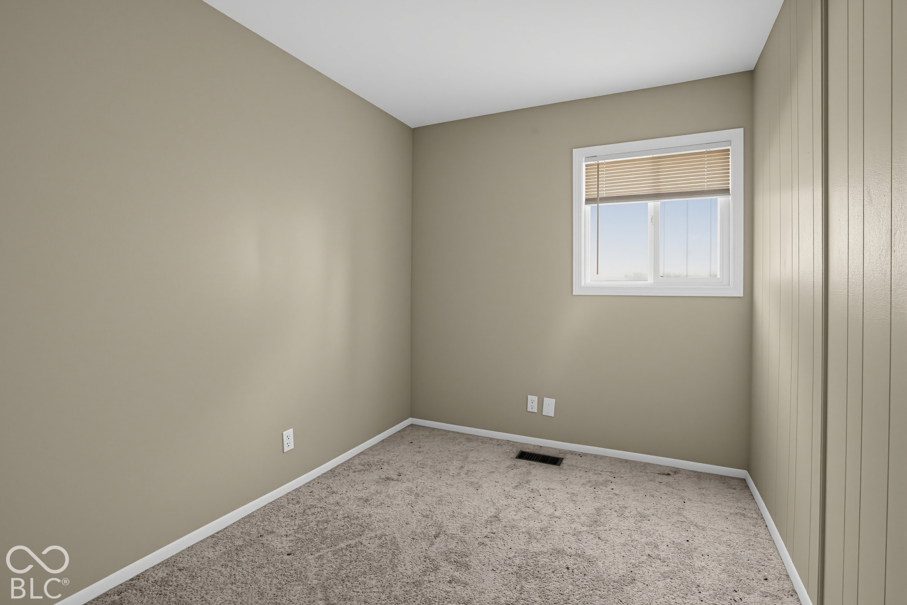 Neutral-toned interior featuring textured wall paneling, wall-to-wall carpeting, and a single-pane window