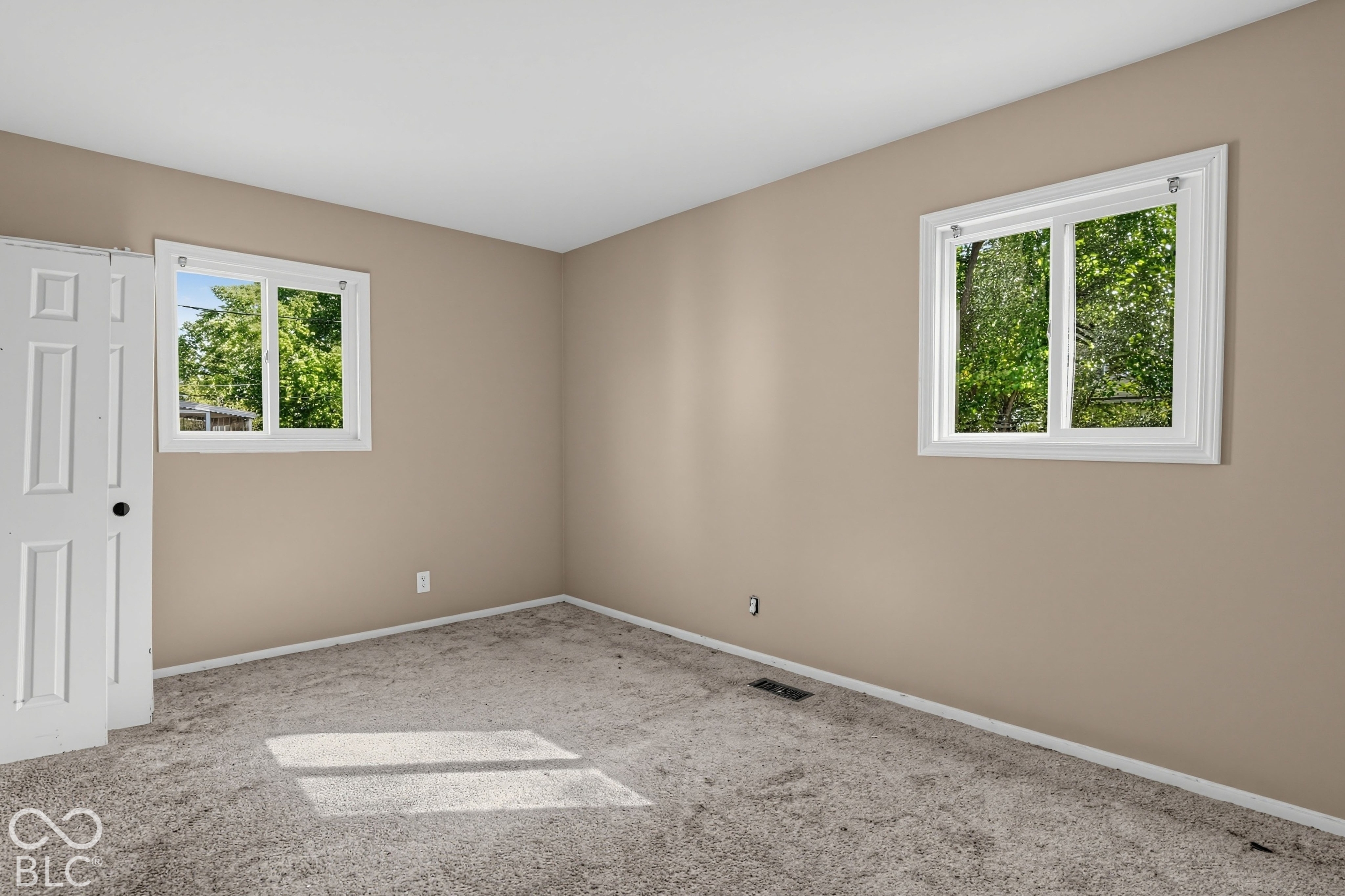 Room featuring neutral wall tones, two dual-pane sliding windows, and a built-in folding closet door